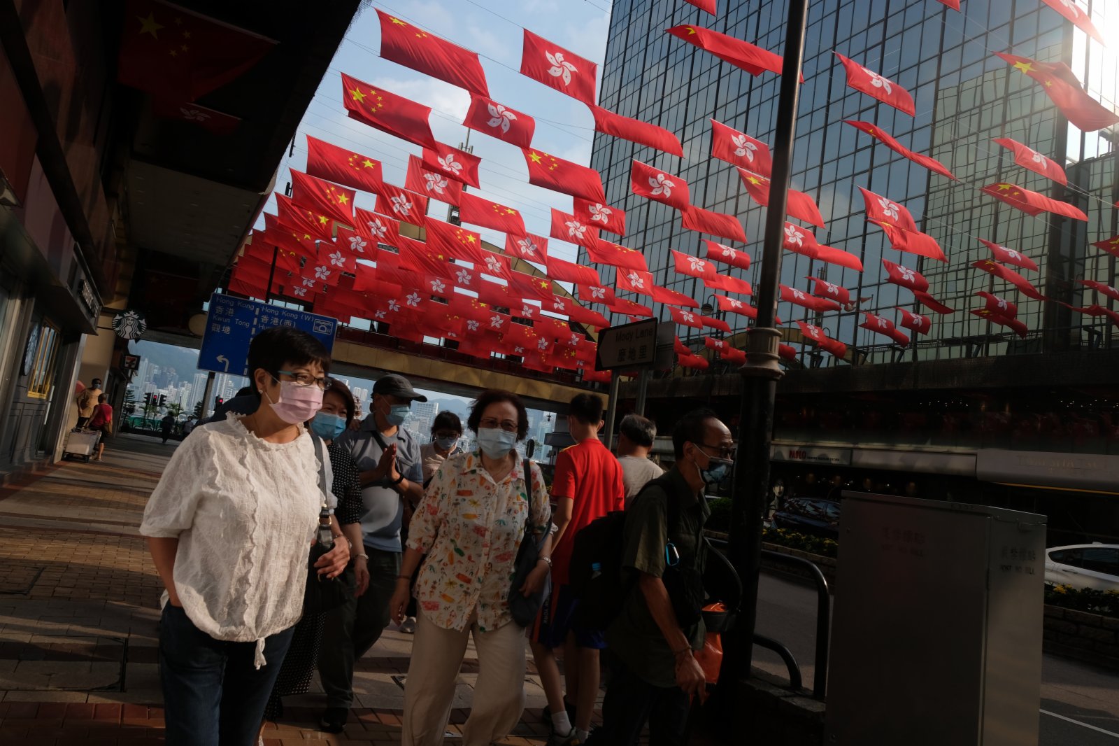 市民路過一排火紅的國旗和區旗。（大公文匯全媒體記者 麥鈞傑 攝）