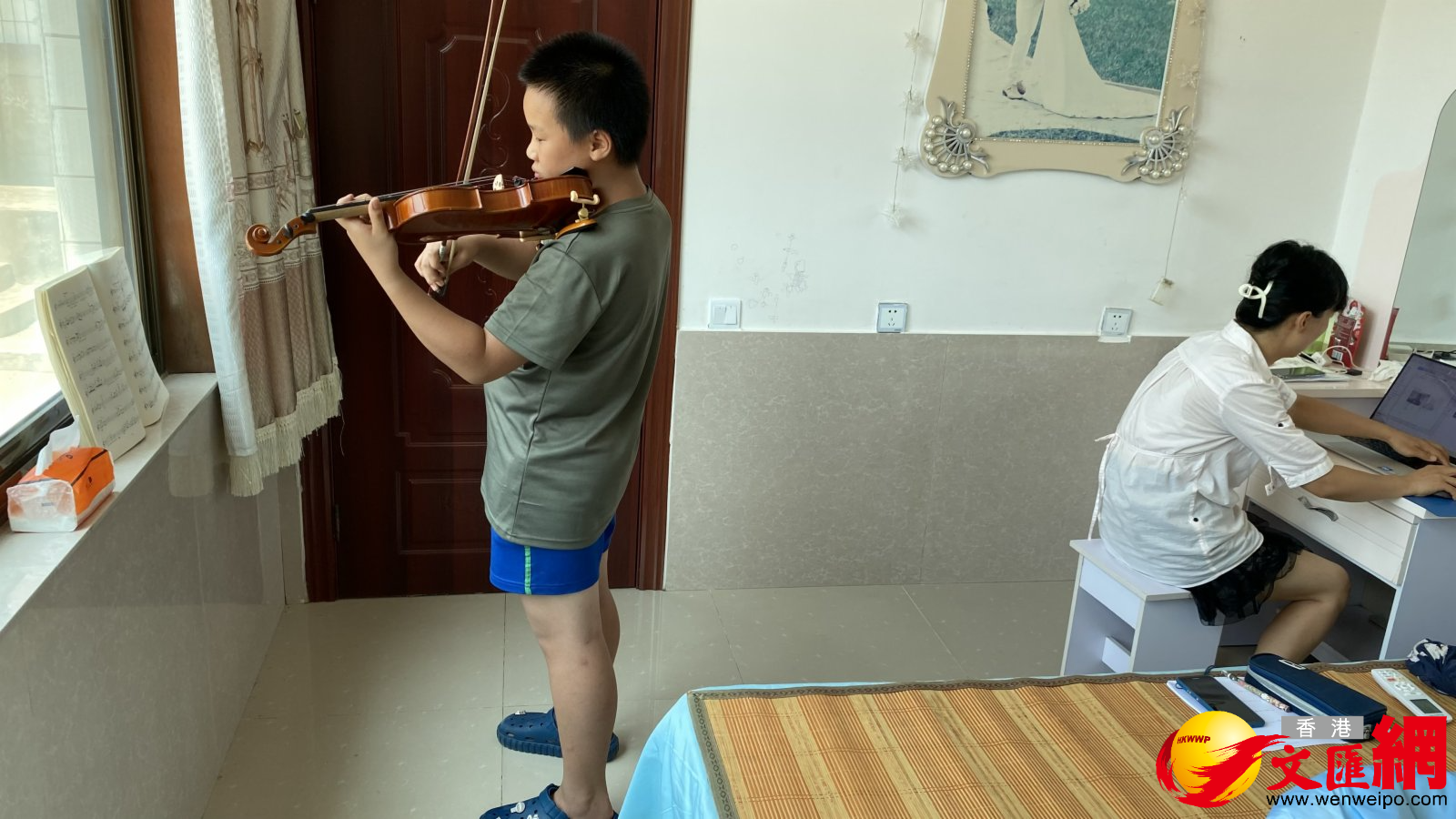 北京小學生在農家練習小提琴，媽媽在一旁備課。（香港文匯網記者顧大鵬 攝）