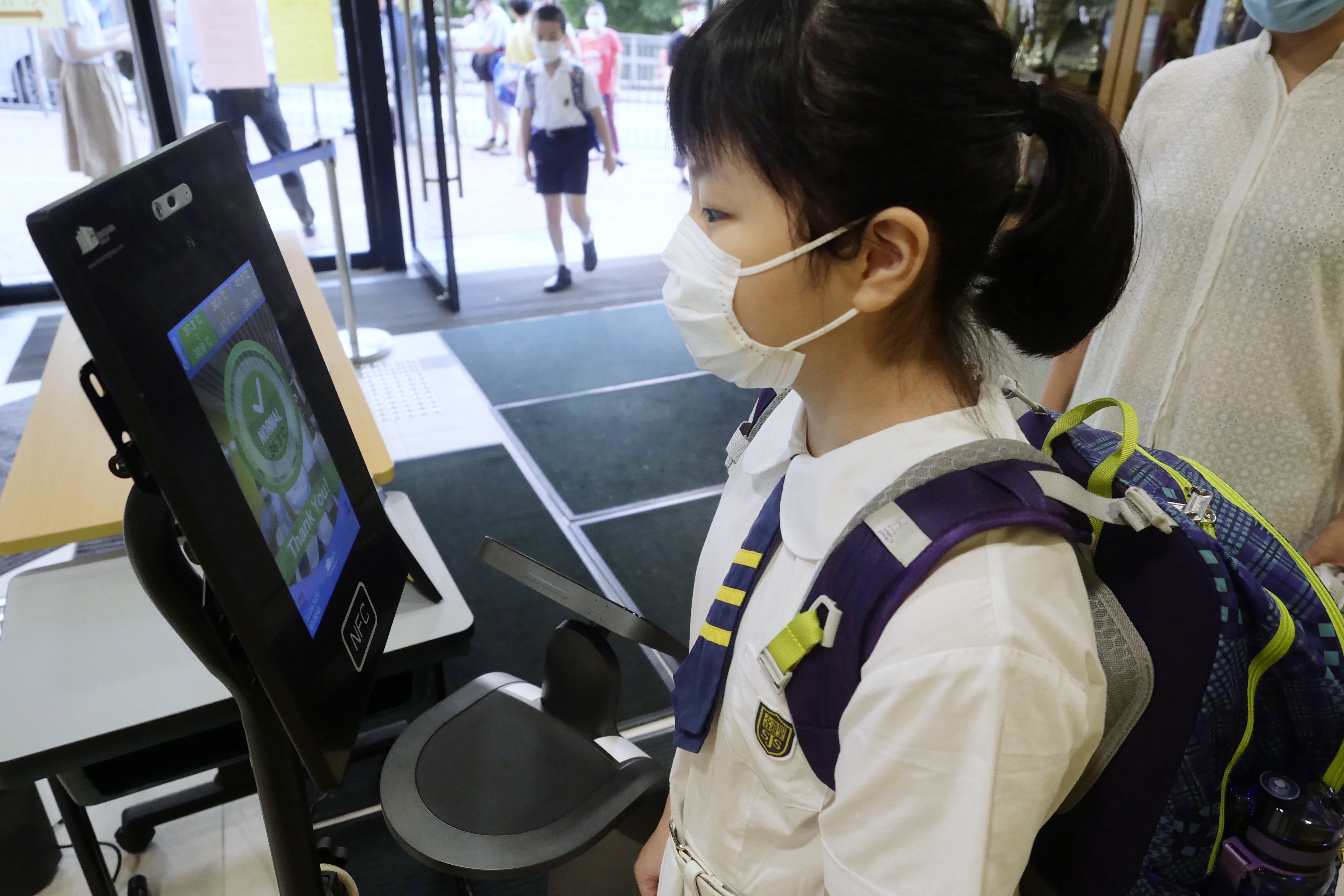9月23日，在位於香港灣仔的聖公會聖雅各小學，小學生進校前測量體溫。（新華社記者 王申 攝）