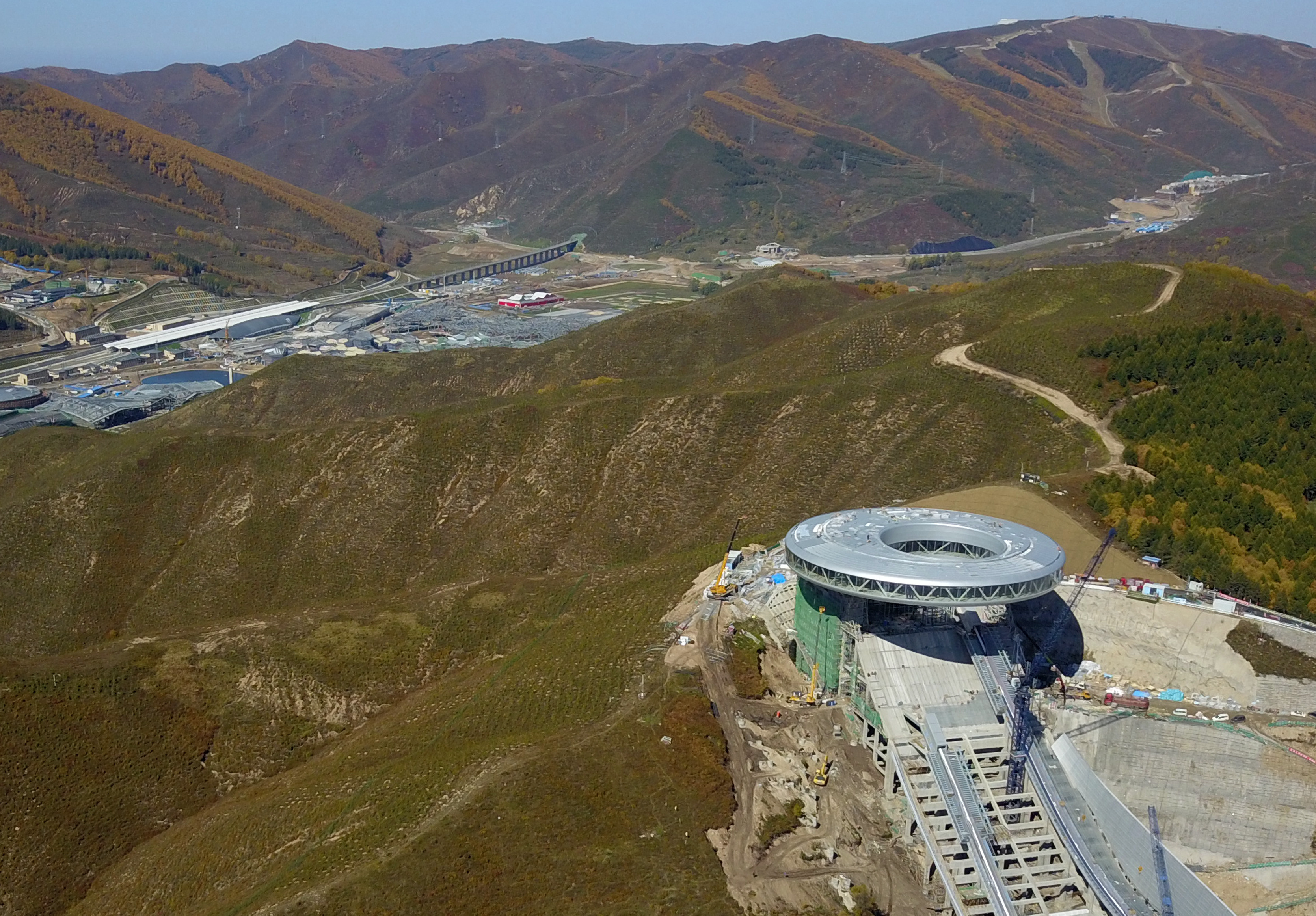 正在建設中的國家跳台滑雪中心與不遠處的京張高鐵太子城站。（新華社）