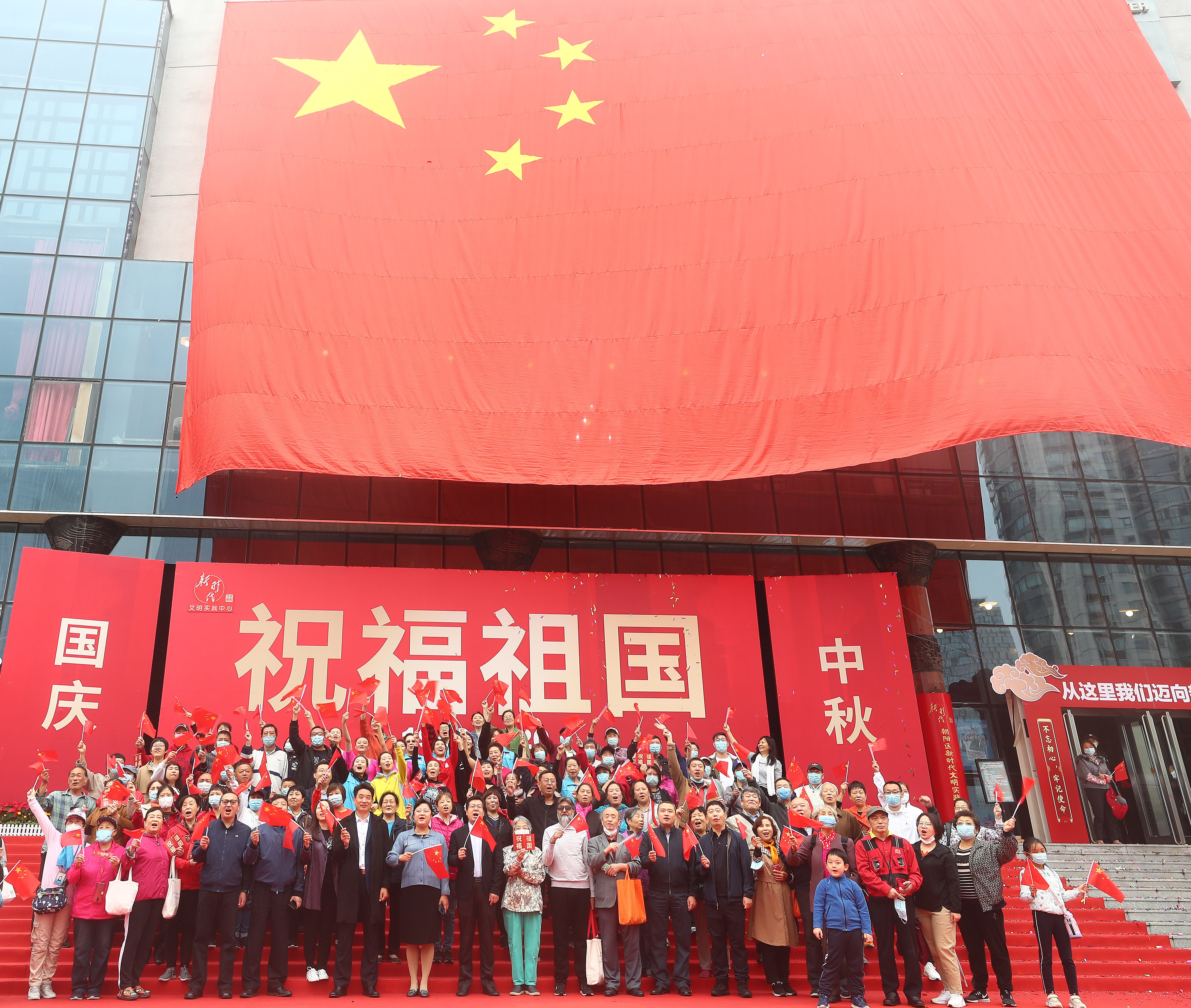 在北京市朝陽區文化館舉辦的國慶專題活動上,嘉賓與國旗合影(10月1日攝)。(新華社)