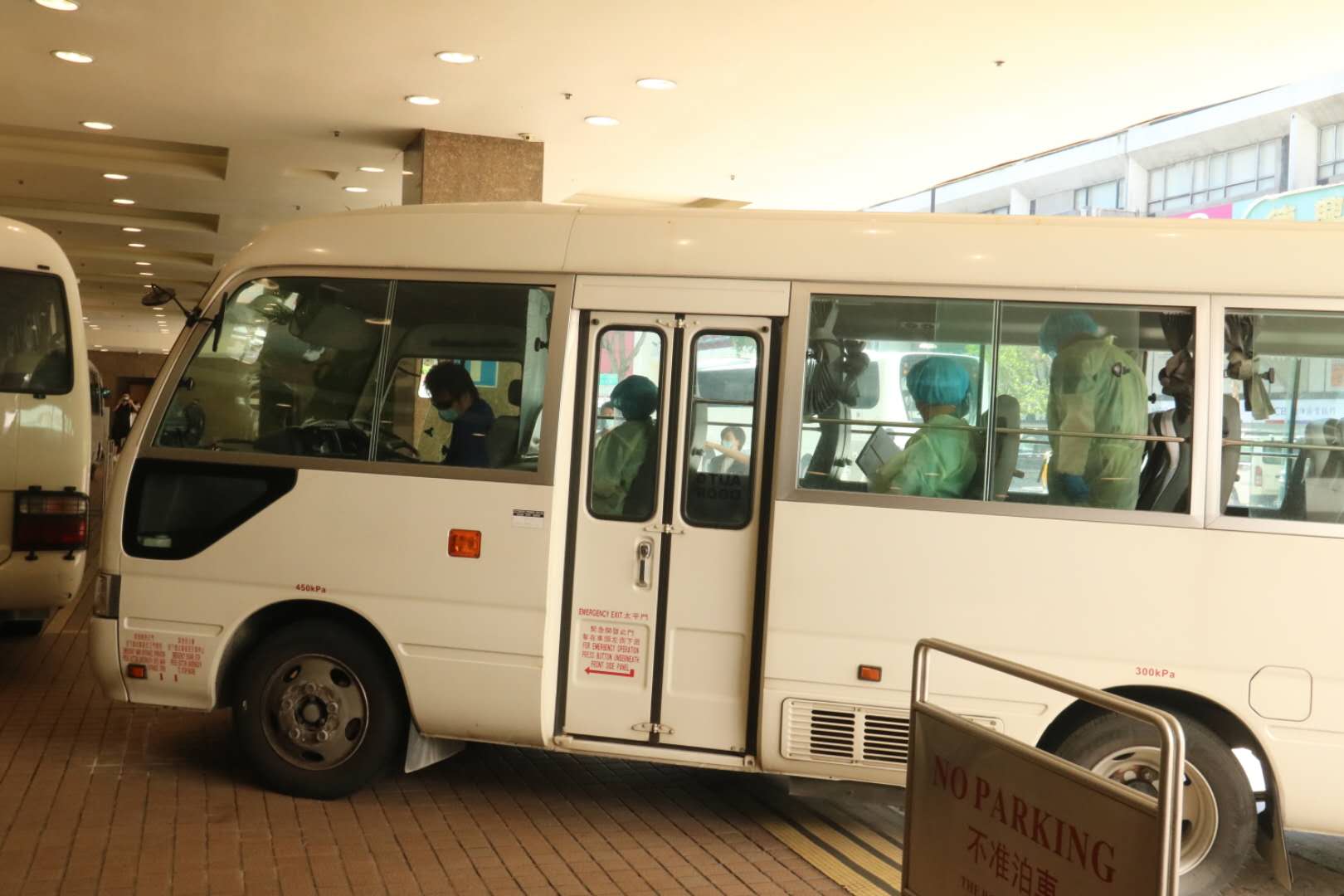 衞生署安排3輛中型旅遊巴,接載酒店員工去往檢疫中心。(大公文匯全媒體記者 攝)
