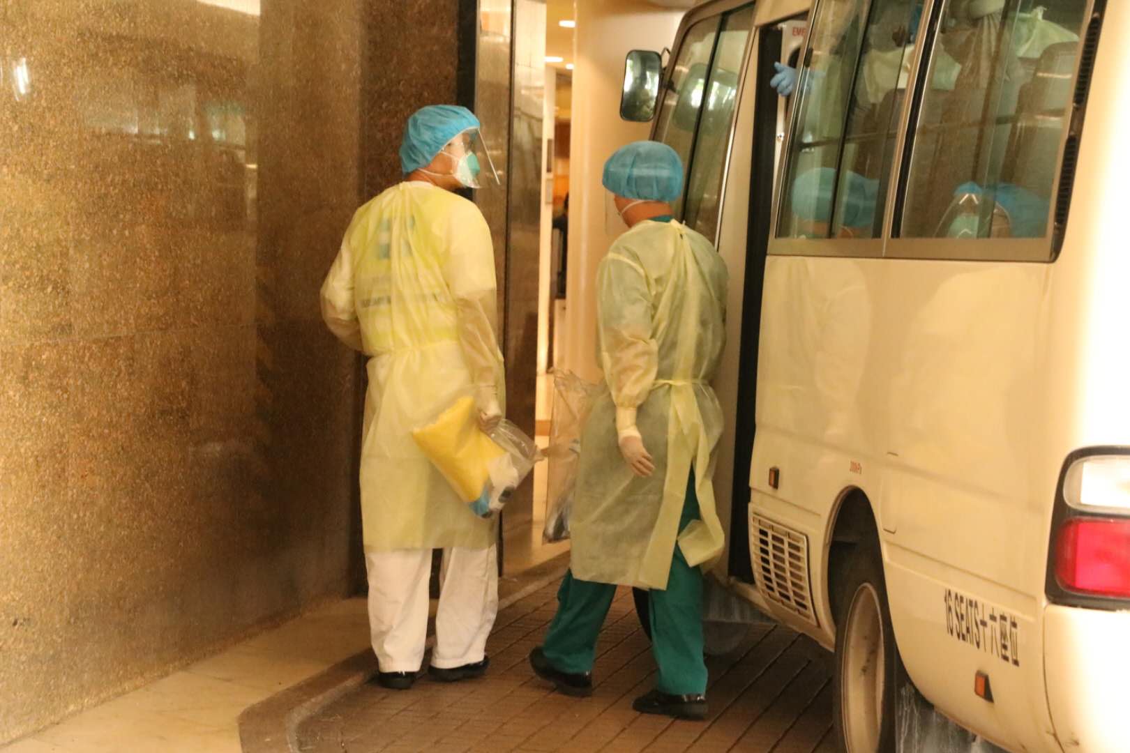 衞生署安排3輛中型旅遊巴,接載酒店員工去往檢疫中心。(大公文匯全媒體記者 攝)