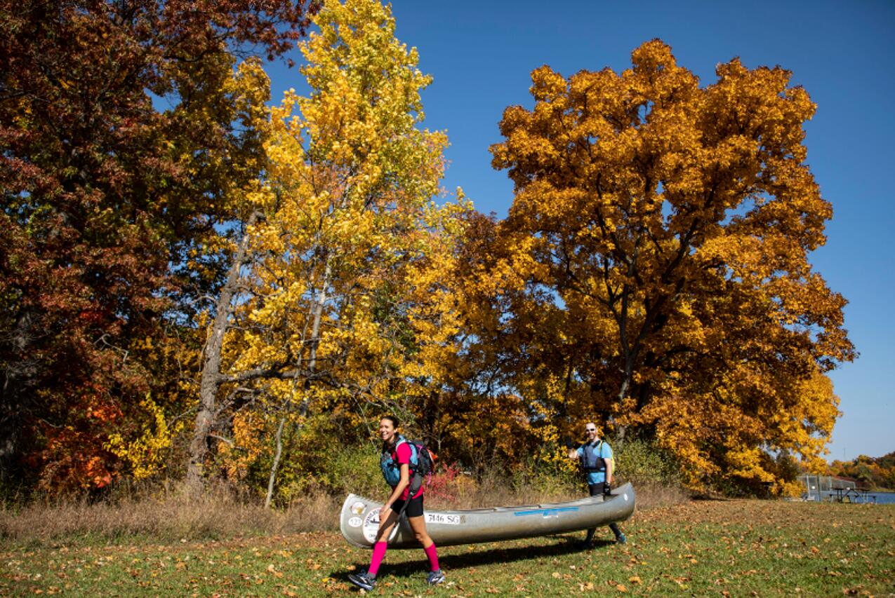10月11日，在美國密歇根州東部利文斯頓縣，人們向河畔搬運獨木舟。(新華社)