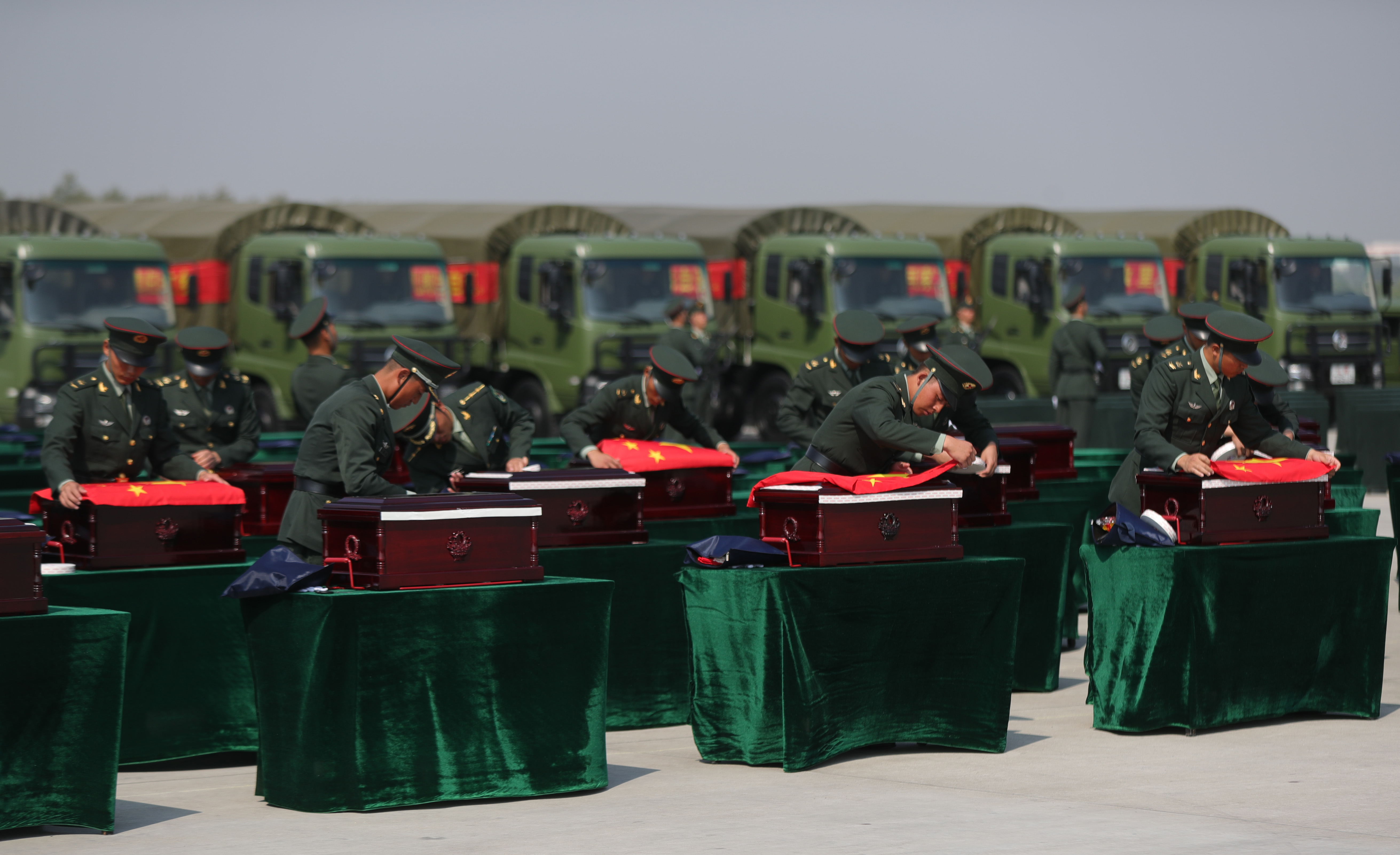 9月27日，在瀋陽桃仙國際機場，禮兵在殮放志願軍烈士遺骸的棺槨上蓋上國旗。（新華社圖片）