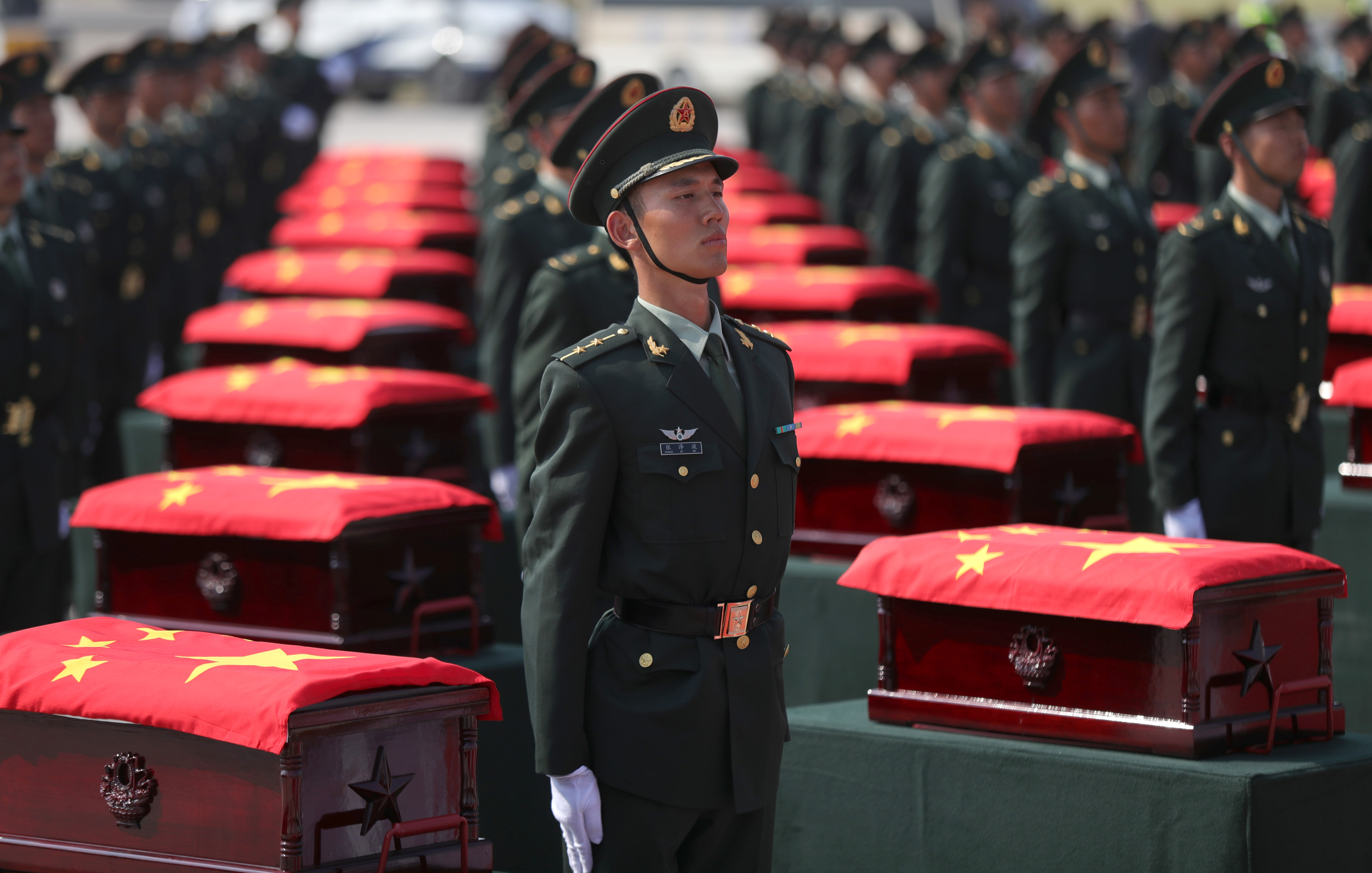 9月27日，在瀋陽桃仙國際機場，禮兵將殮放志願軍烈士遺骸的棺槨從專機上護送至棺槨擺放區。（新華社圖片）