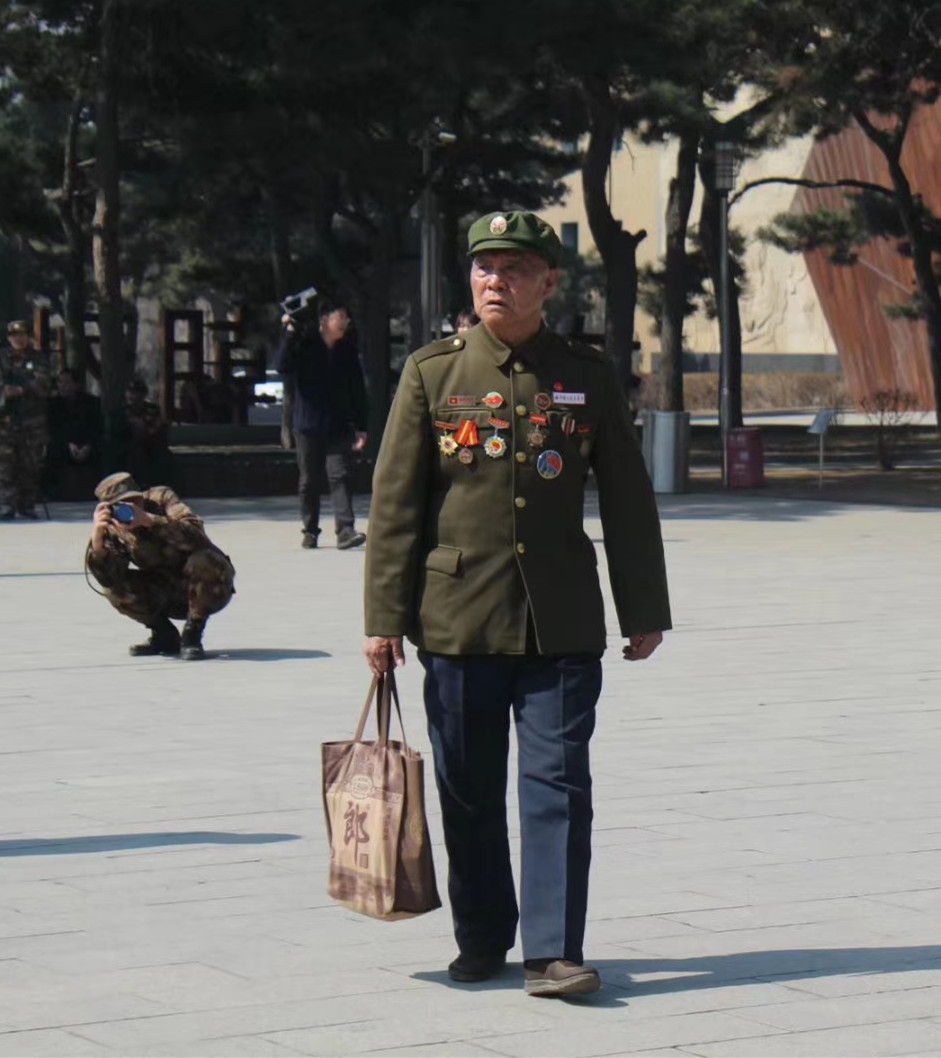 高磊（後）在抗美援朝烈士陵園為前來掃墓的老兵李維波拍照。（受訪者供圖）