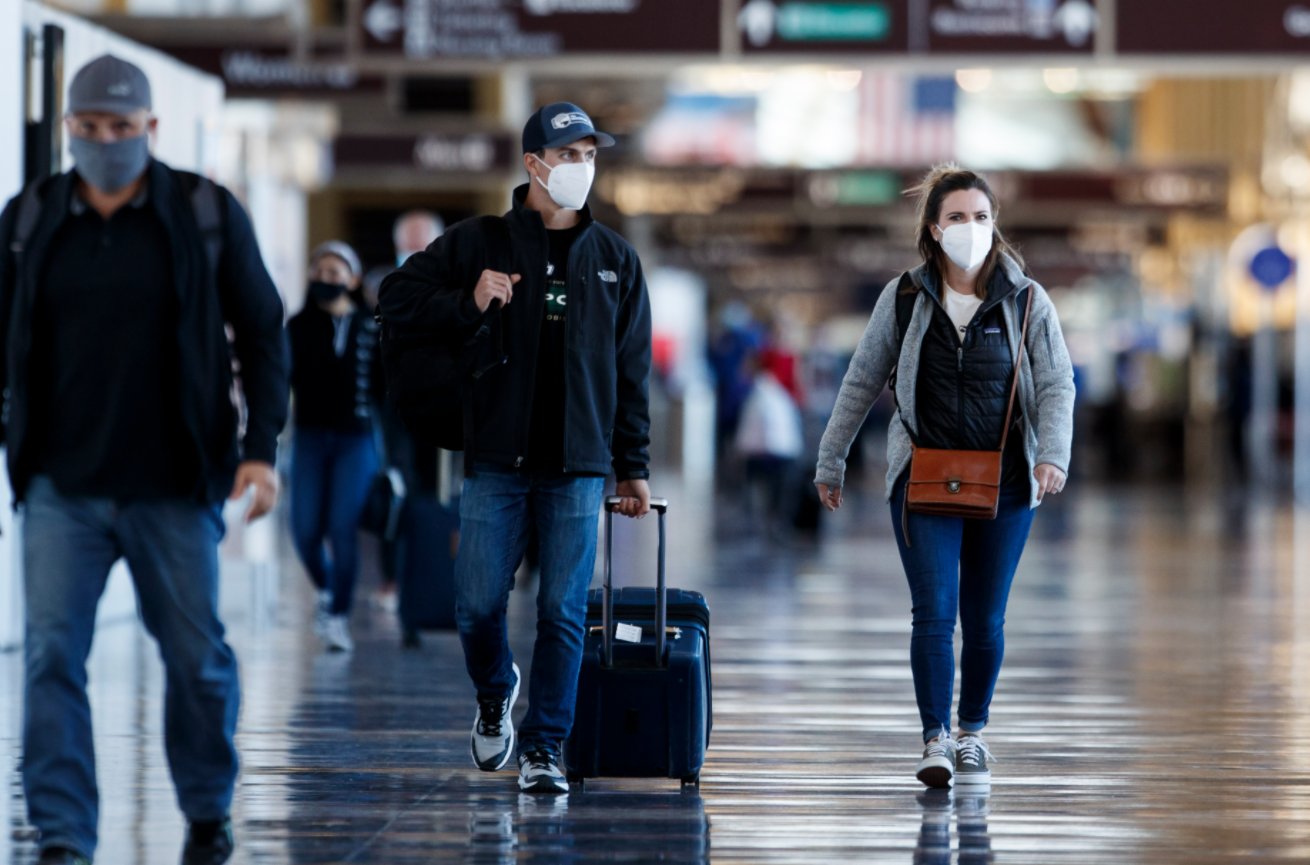 11月24日，戴口罩的旅客走在美國弗吉尼亞州阿靈頓的里根國家機場。（新華社）