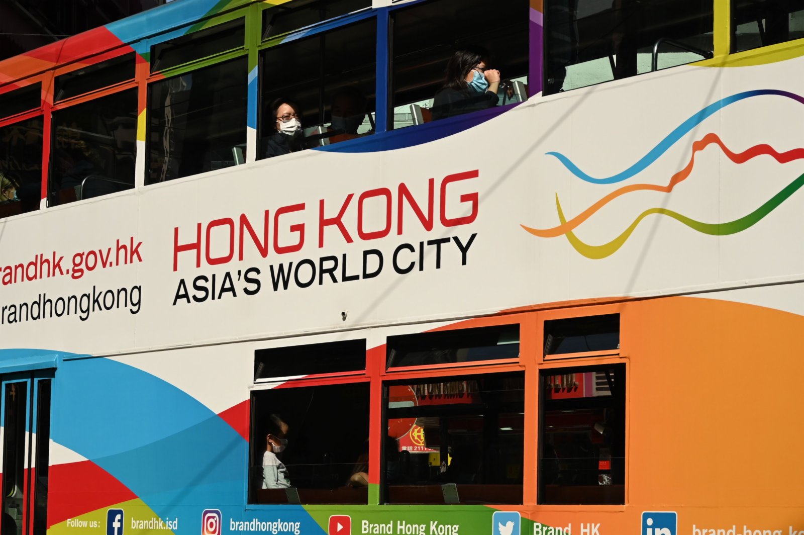 在香港街頭，市民戴着口罩乘坐有軌電車。（法新社圖片）