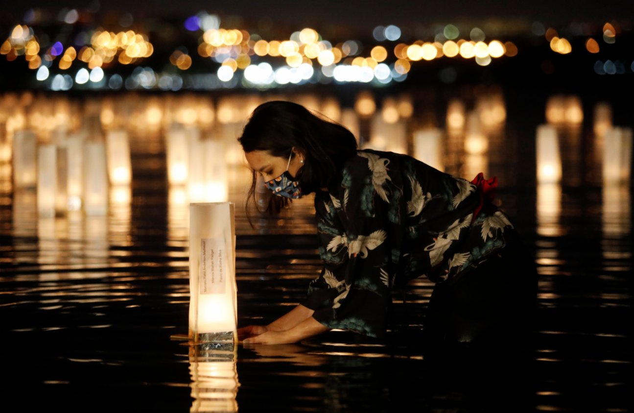 11月30日，在巴西首都巴西利亞，一名女子往湖中放入水燈。（新華社）