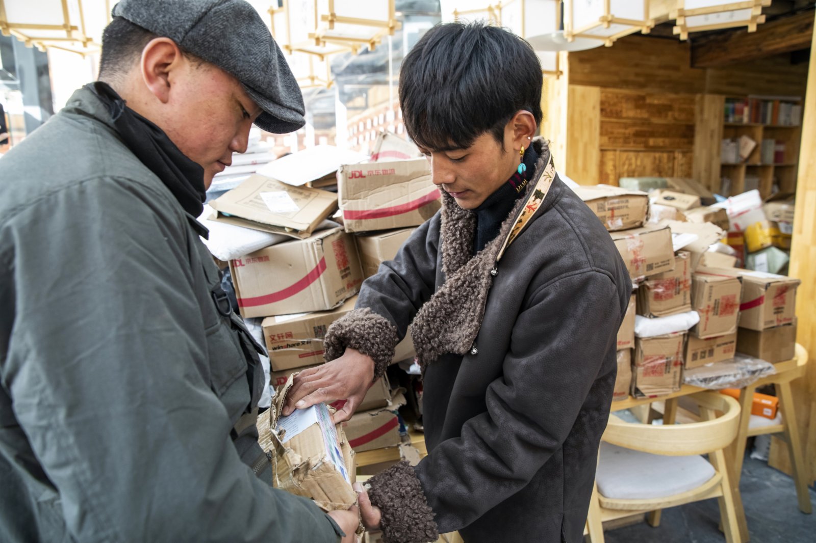 在理塘縣勒通古鎮的倉央嘉措微型博物館的倉央書房，丁真（右）拆開網友寄給他的禮物，身後堆放的是全國各地網友寄來的禮物。