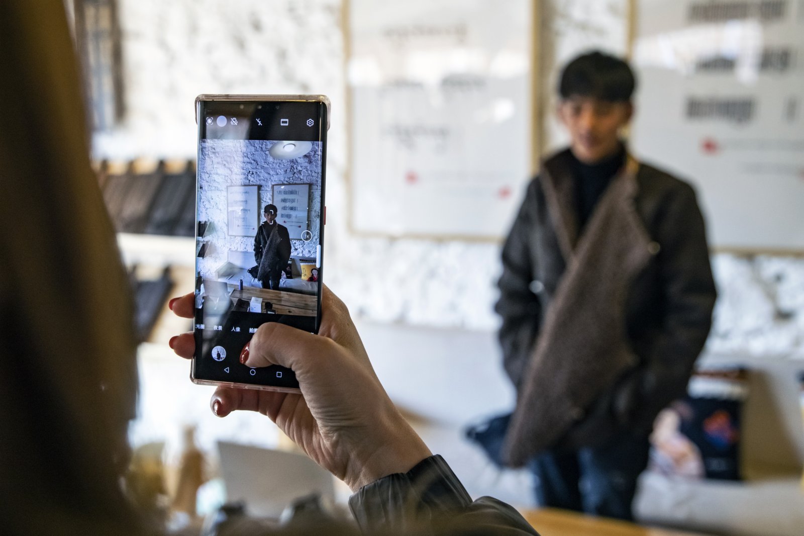 在理塘縣勒通古鎮的倉央嘉措微型博物館，一名從外地趕來的粉絲用手機給丁真拍照。這裏將是丁真未來的工作場所之一。