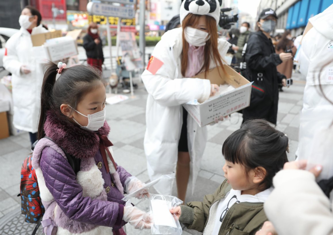 2月29日,在日本東京的池袋站前,在日華僑華人志願者團體「口罩熊貓行動小組」向當地民眾免費發放口罩,一名小志願者(左)將兒童用口罩送給日本小朋友。(新華社) 2月29日,在日本東京的池袋站前,在日華僑華人志願者團體「口罩熊貓行動小組」向當地民眾免費發放口罩,一名小志願者(左)將兒童用口罩送給日本小朋友。(新華社)