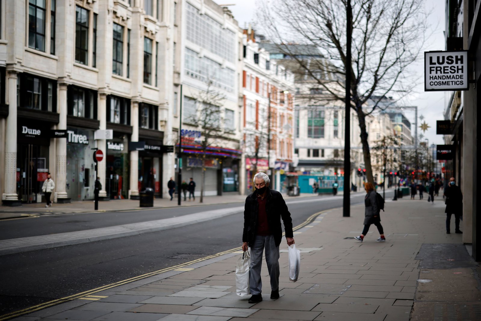當地時間2020年12月22日，英國倫敦，「封城」之後街頭人跡罕至，少數行人出行佩戴口罩。
