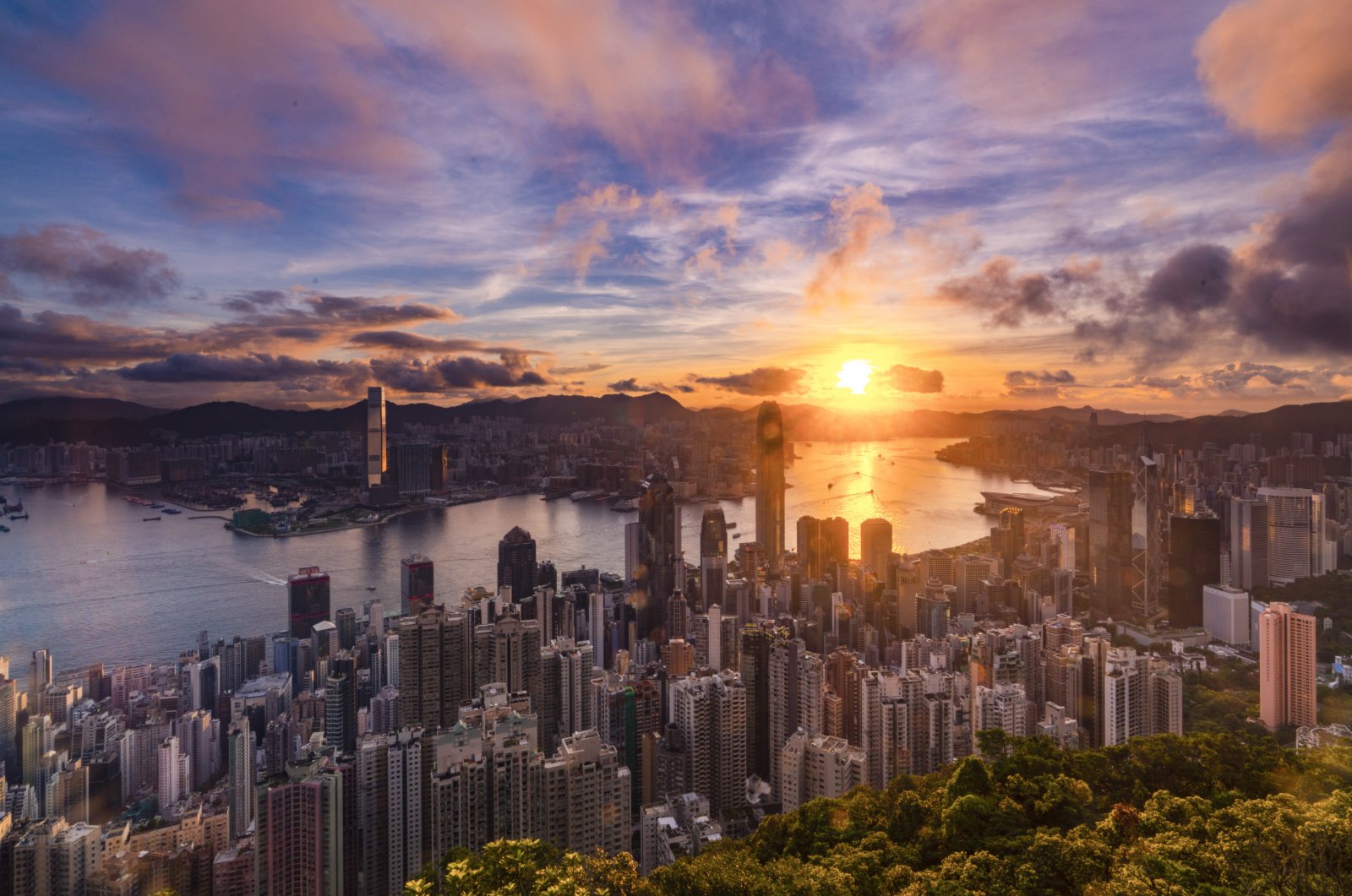 2020年6月30日早晨，一陣驟雨過後，籠罩在香港上空的烏雲逐漸消散，一輪朝陽在東方噴薄而出，曙光照耀維港兩岸。（中新社）
