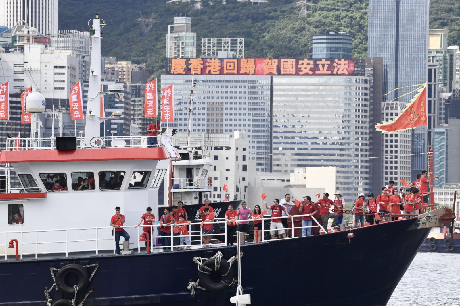 7月1日，香港維多利亞港兩岸的戶外顯示屏不斷播放「慶香港回歸 賀國安立法」的標語，與此同時，近百艘懸掛相同標語的漁船在海上巡遊，共同慶祝《香港國安法》頒布。（中新社）