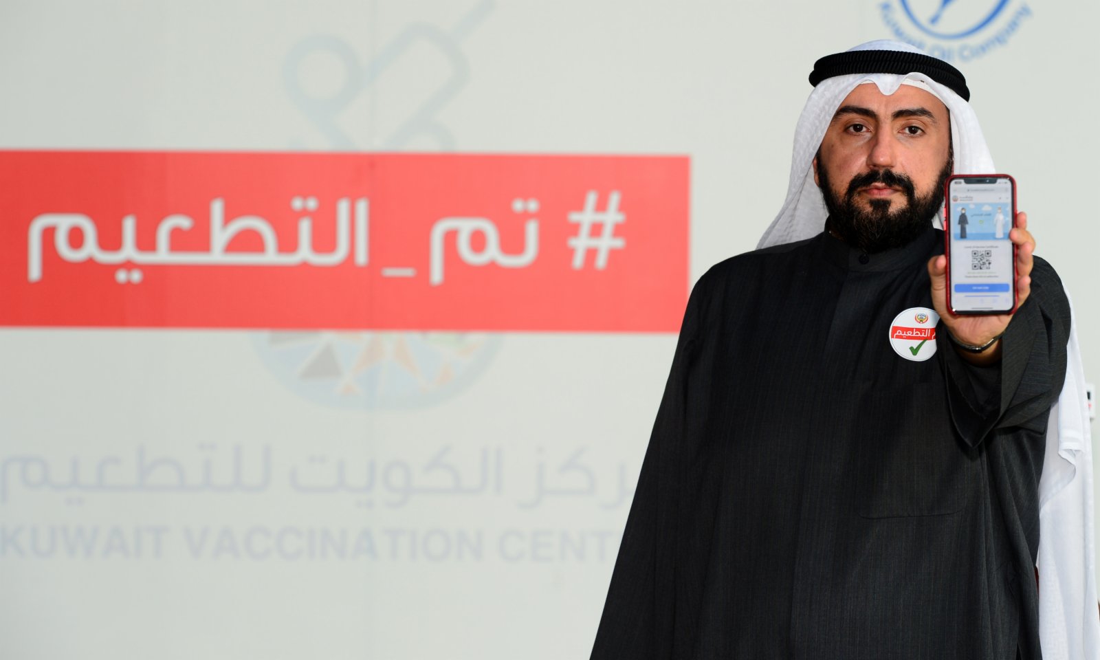 1月14日，在科威特哈瓦利省的新冠疫苗接種中心，科威特衞生大臣巴西勒·薩巴赫接種新冠疫苗後展示接種證書。（新華社）