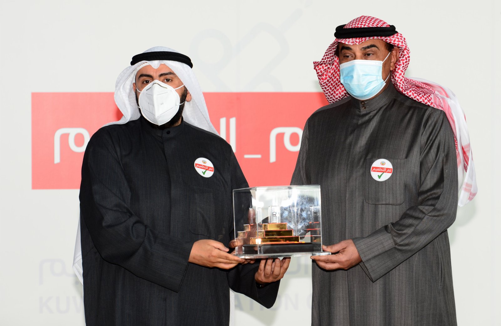 1月14日，在科威特哈瓦利省的新冠疫苗接種中心，科威特衞生大臣巴西勒·薩巴赫（左）將新冠疫苗交給科威特首相薩巴赫。（新華社）