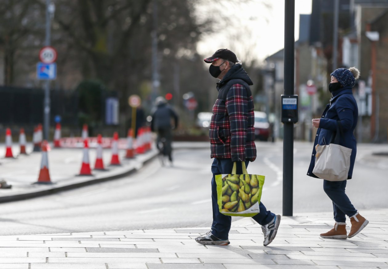 1月21日，戴口罩的人們走在英國泰晤士河畔金斯頓街頭。（新華社）