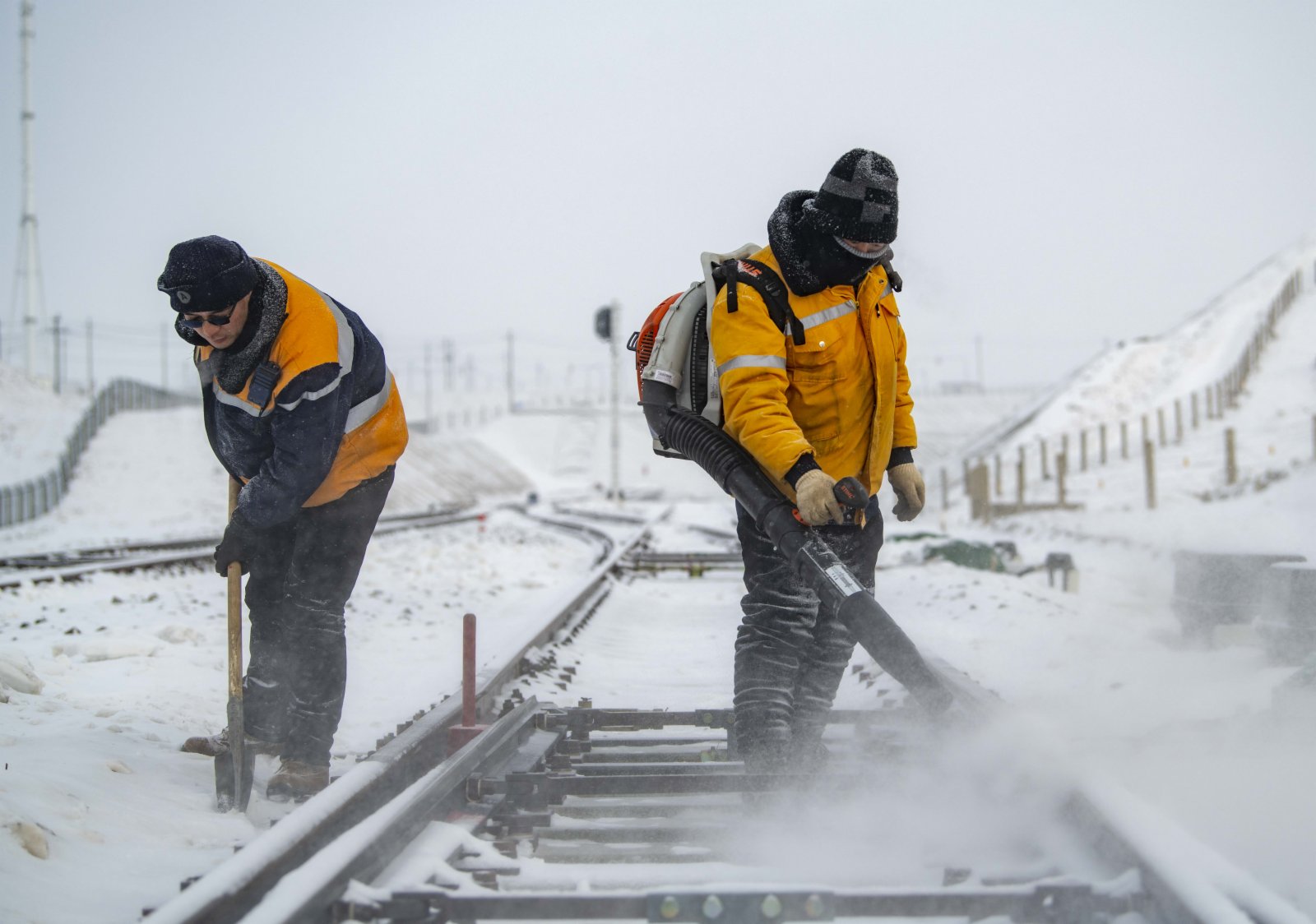 鐵廠溝維修工隊的工人王天兵（左）和工友在清除一處鐵軌道岔上的積雪。（新華社）