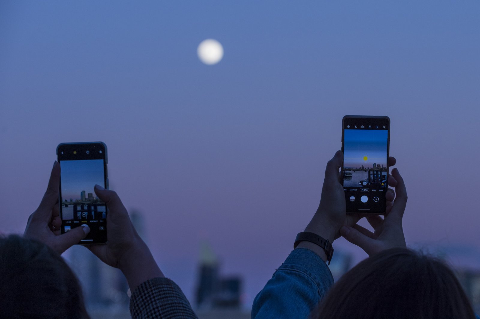 2月26日，人們在英國倫敦用手機拍攝圓月。新華社