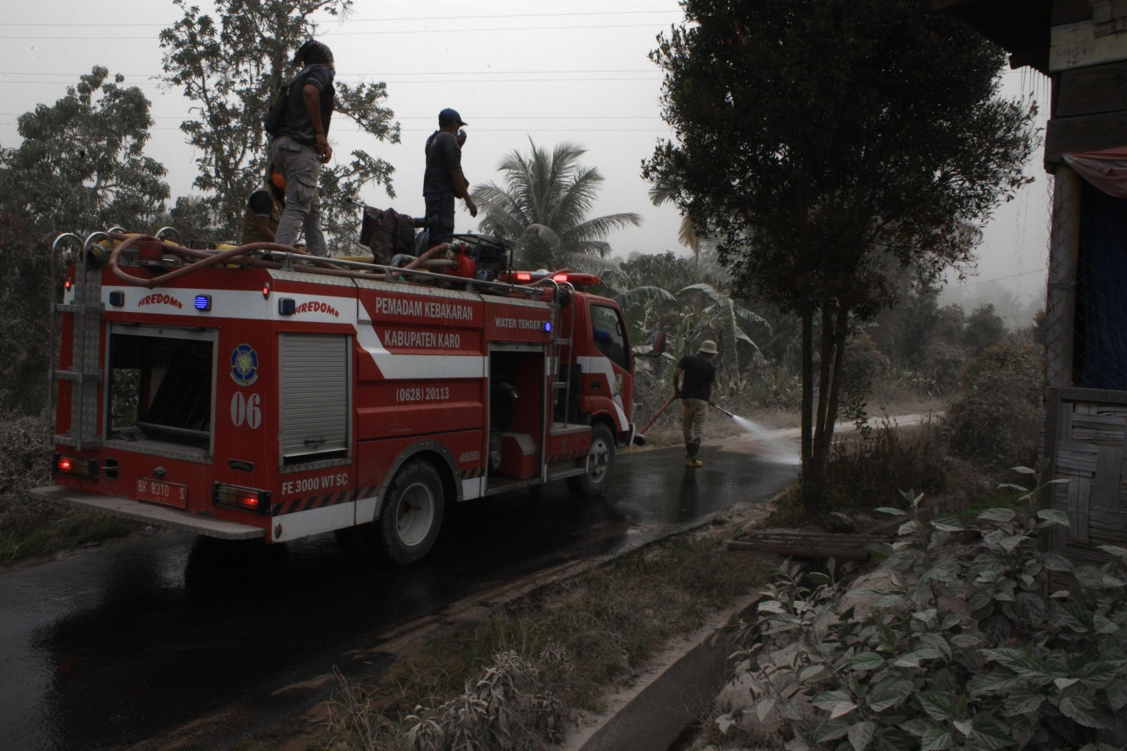 3月2日，印度尼西亞北蘇門答臘省卡羅的消防員清洗被火山灰覆蓋的道路。