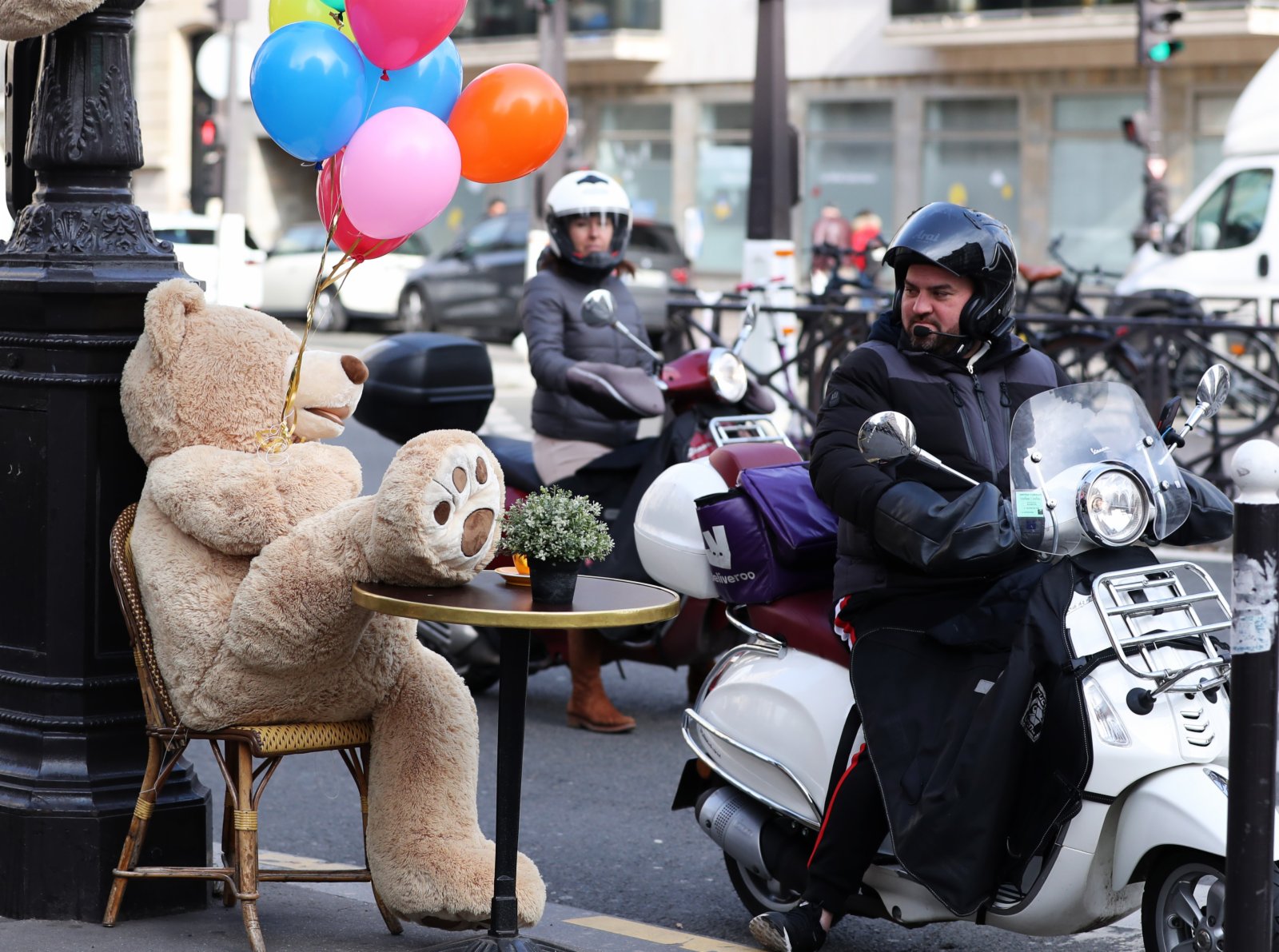 3月3日，一名男子騎摩托車經過法國巴黎街頭一家餐館外的玩具熊。（新華社）