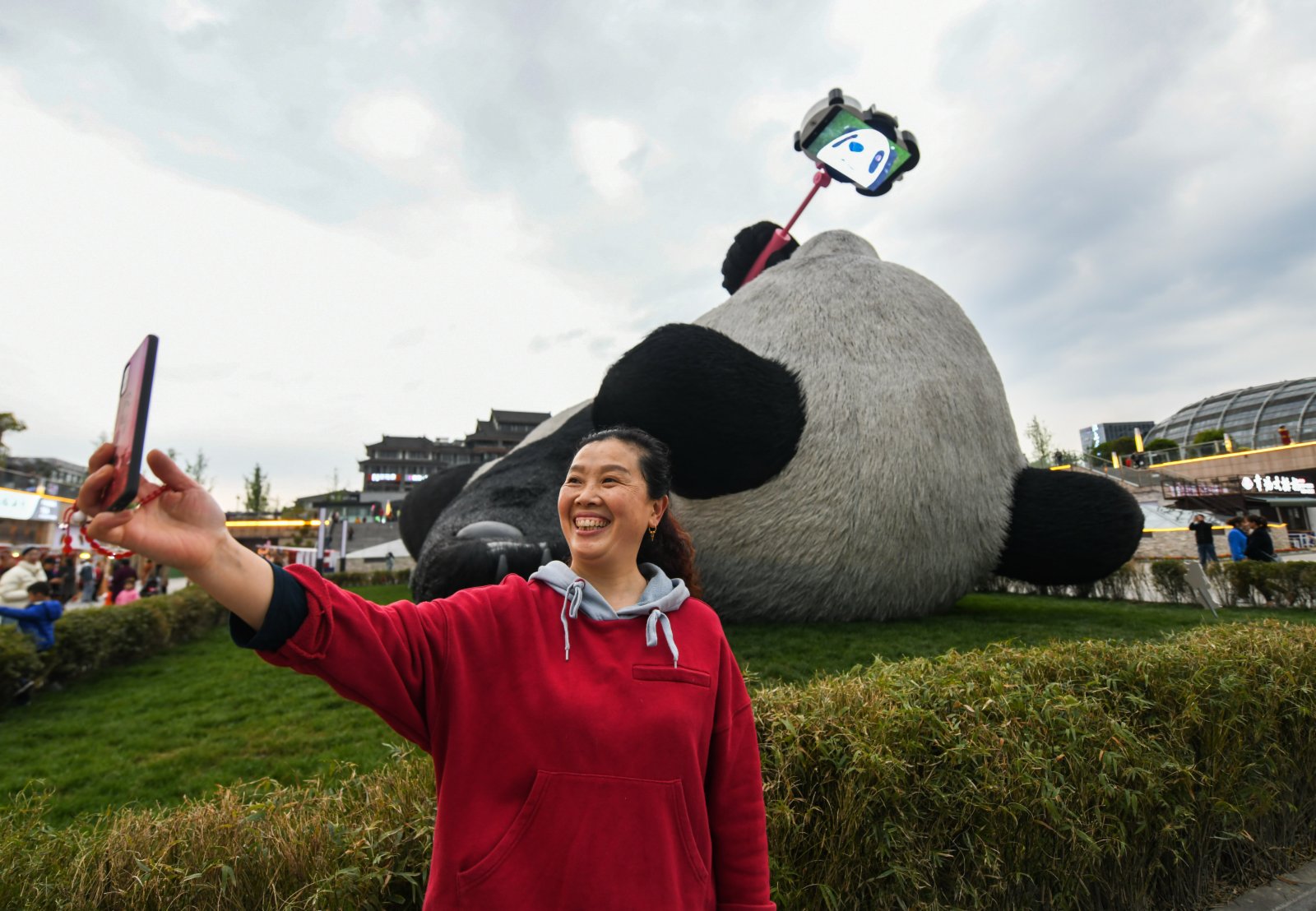 4月7日，在四川省都江堰市仰天窩廣場，一名遊客在「自拍熊貓」雕塑前拍照。（新華社）