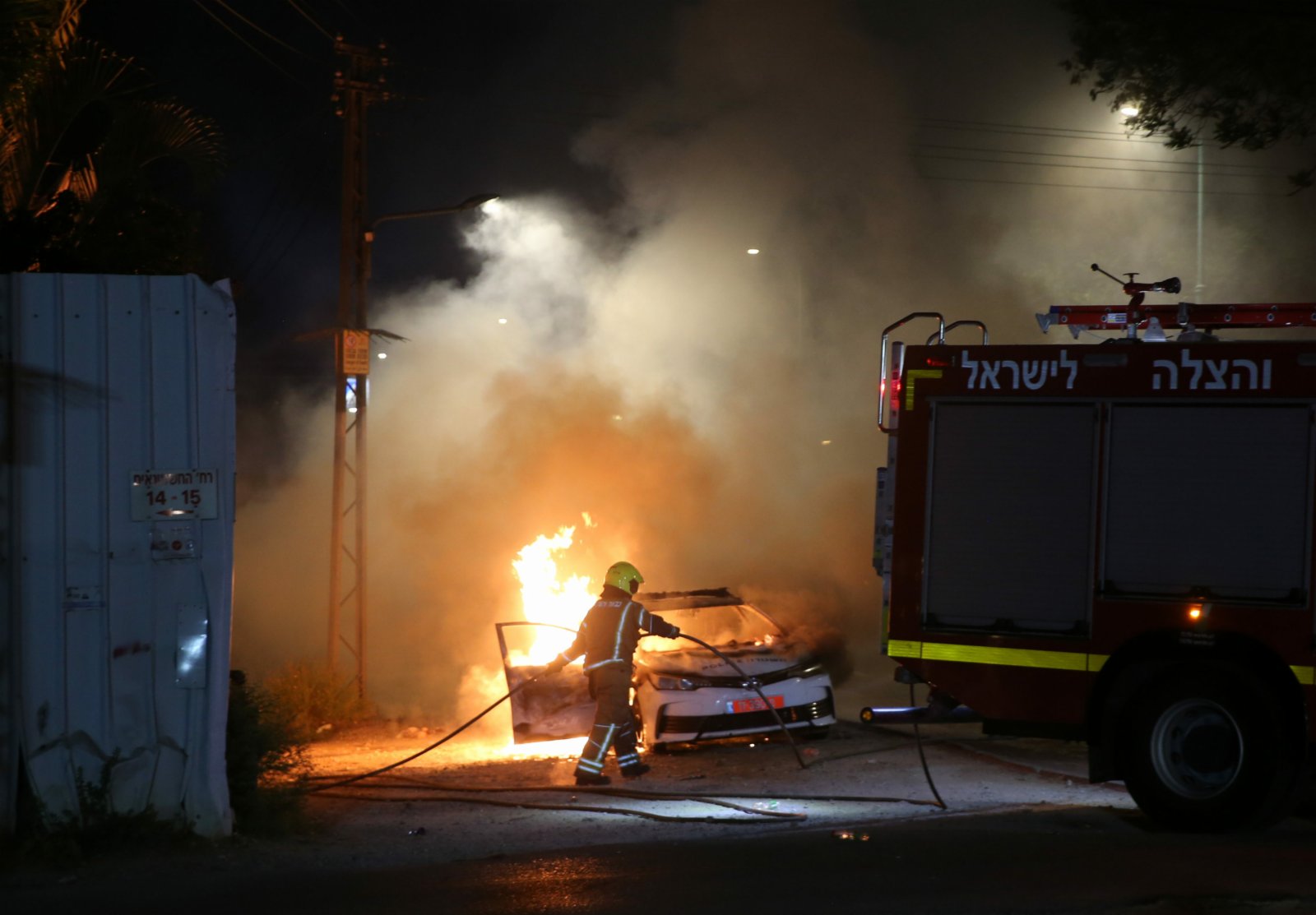 5月12日，在以色列中部城市盧德，消防員準備為一輛燃燒的警車滅火。（新華社）