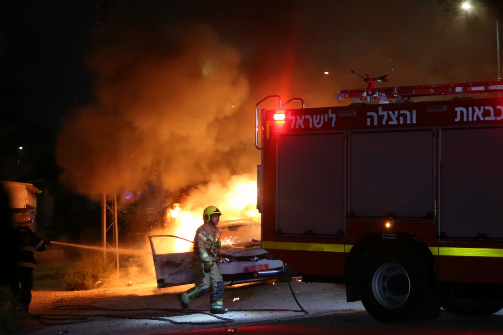 5月12日，在以色列中部城市盧德，消防員為一輛燃燒的警車滅火。（新華社）
