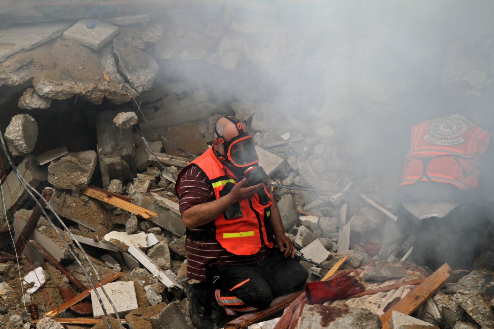 5月16日，巴勒斯坦民防人員在加沙城被炸住宅樓的廢墟中進行搜救。（新華社）