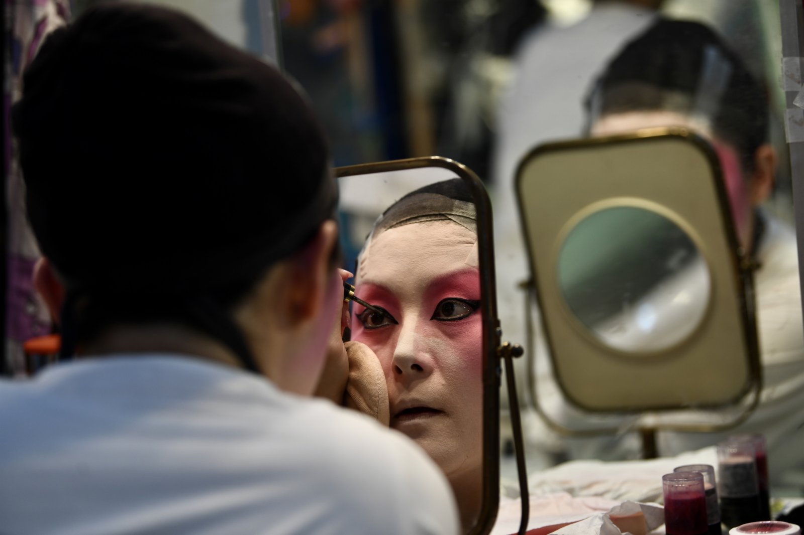圖為表演者畫臉譜準備演出。（中新社）