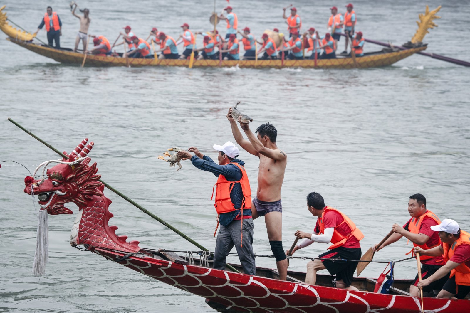 6月12日，參賽龍舟隊在漢江上表演抓鯉魚和活鴨。（新華社）