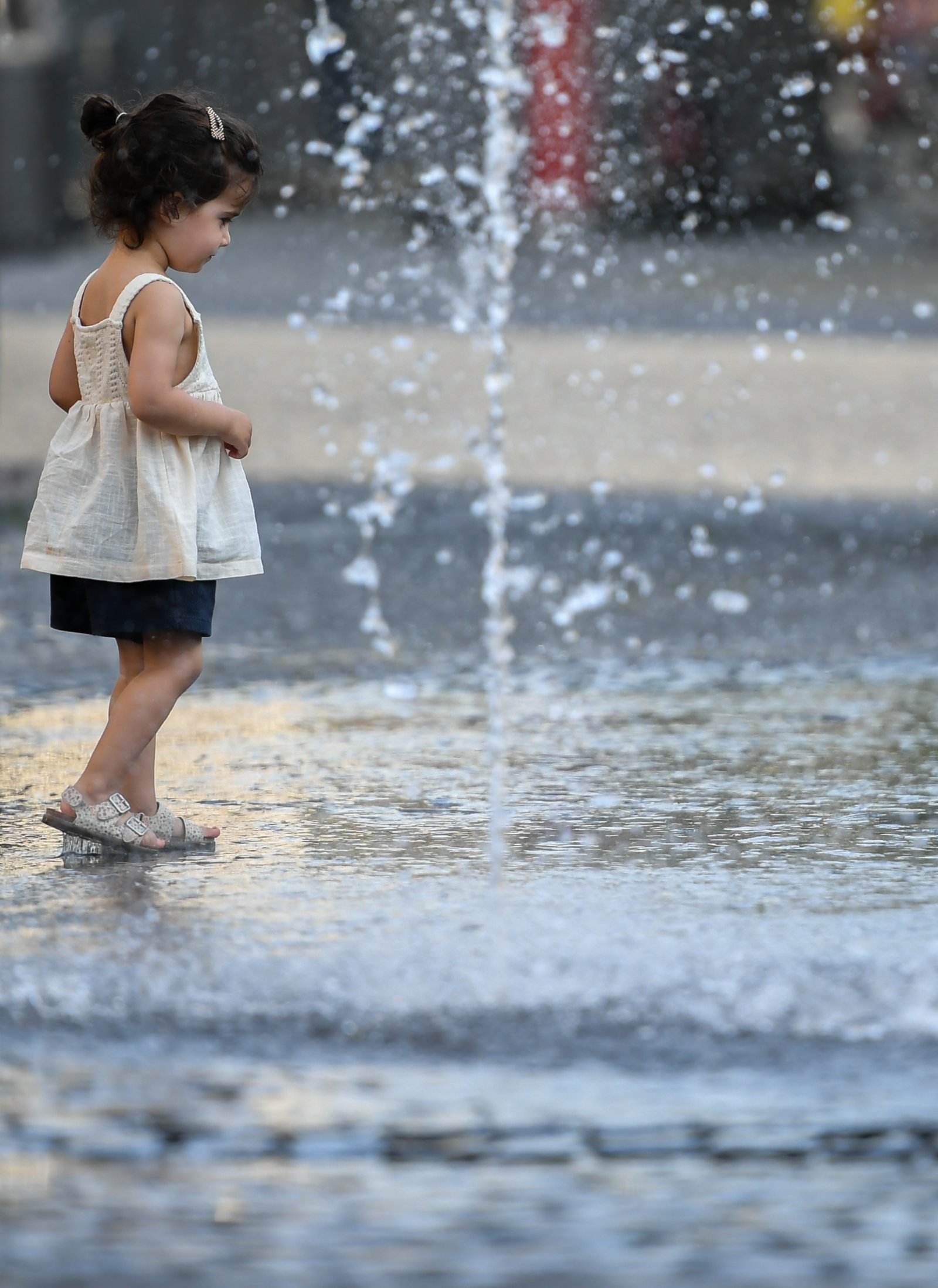 6月17日，在德國法蘭克福，一名兒童在噴泉旁戲水納涼。（新華社）