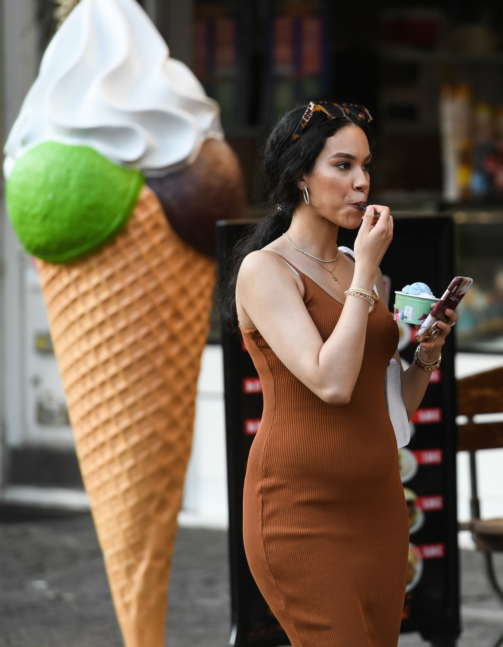 6月17日，在德國法蘭克福，一名女子手拿冰激凌從街頭走過。（新華社）