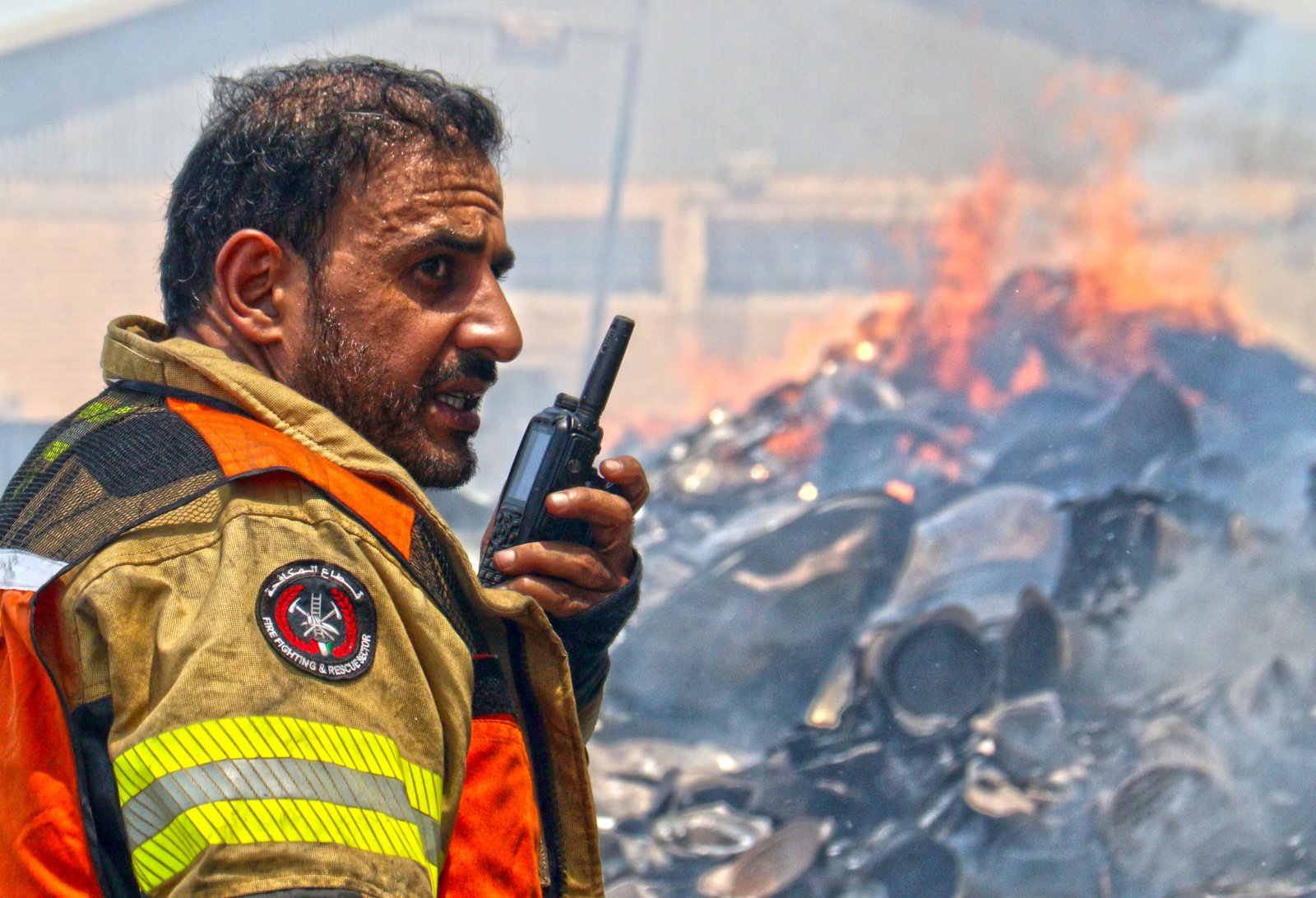 6月19日，一名消防人員在科威特首都省一處倉庫火災現場指揮滅火。（新華社）