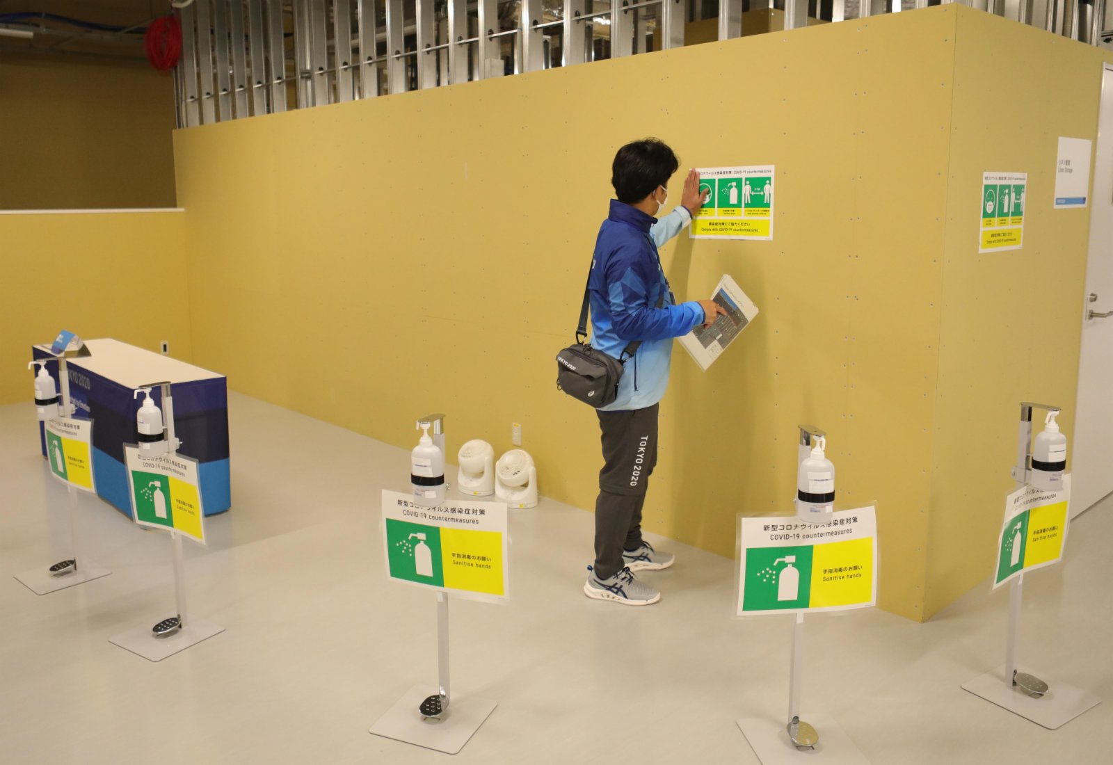 工作人員在東京奧運會奧運村內張貼防疫標誌。（新華社）