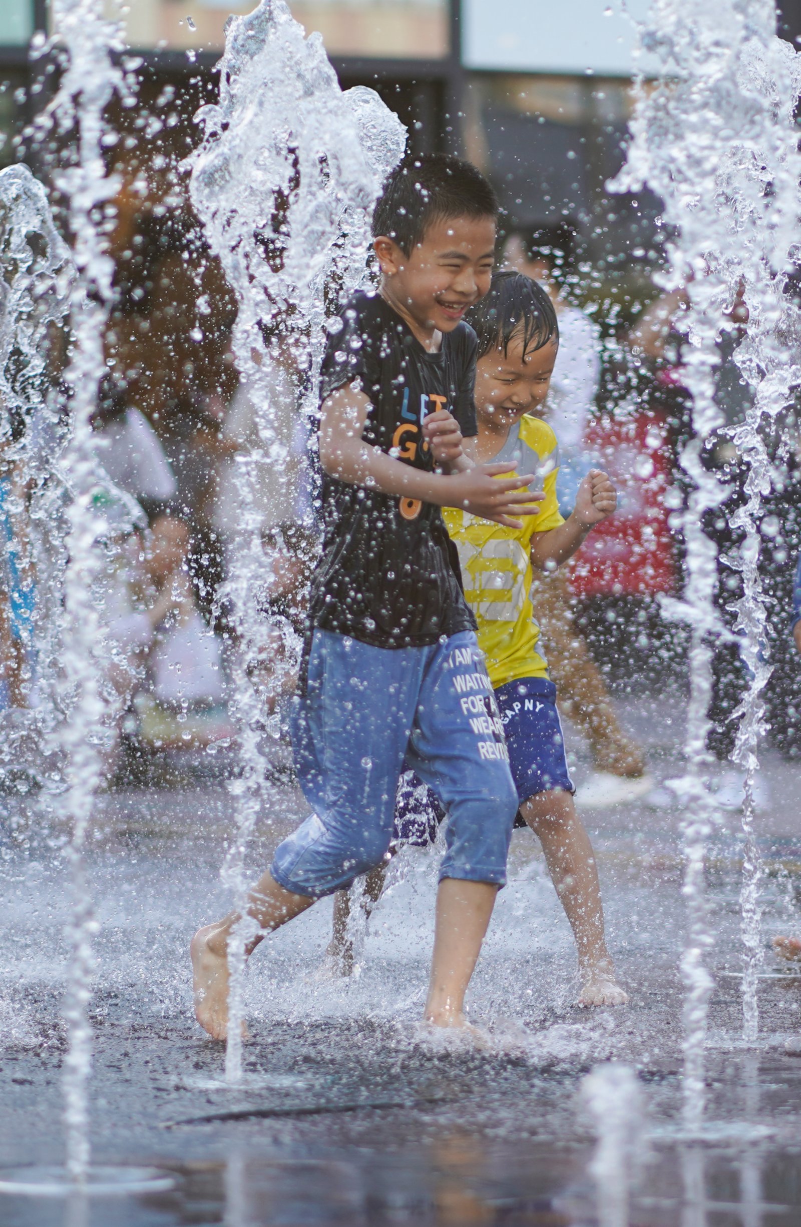 6月20日，孩子們在北京華熙LIVE·五棵松商業街區一處噴泉戲水。（新華社）