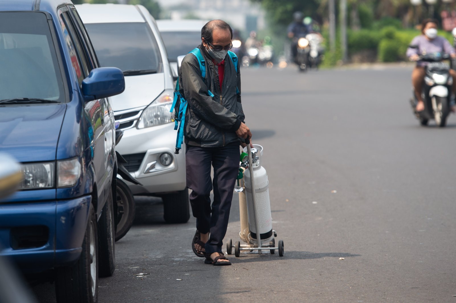  7月5日，一名男子在印度尼西亞雅加達拖着氧氣罐去充氧。（新華社）