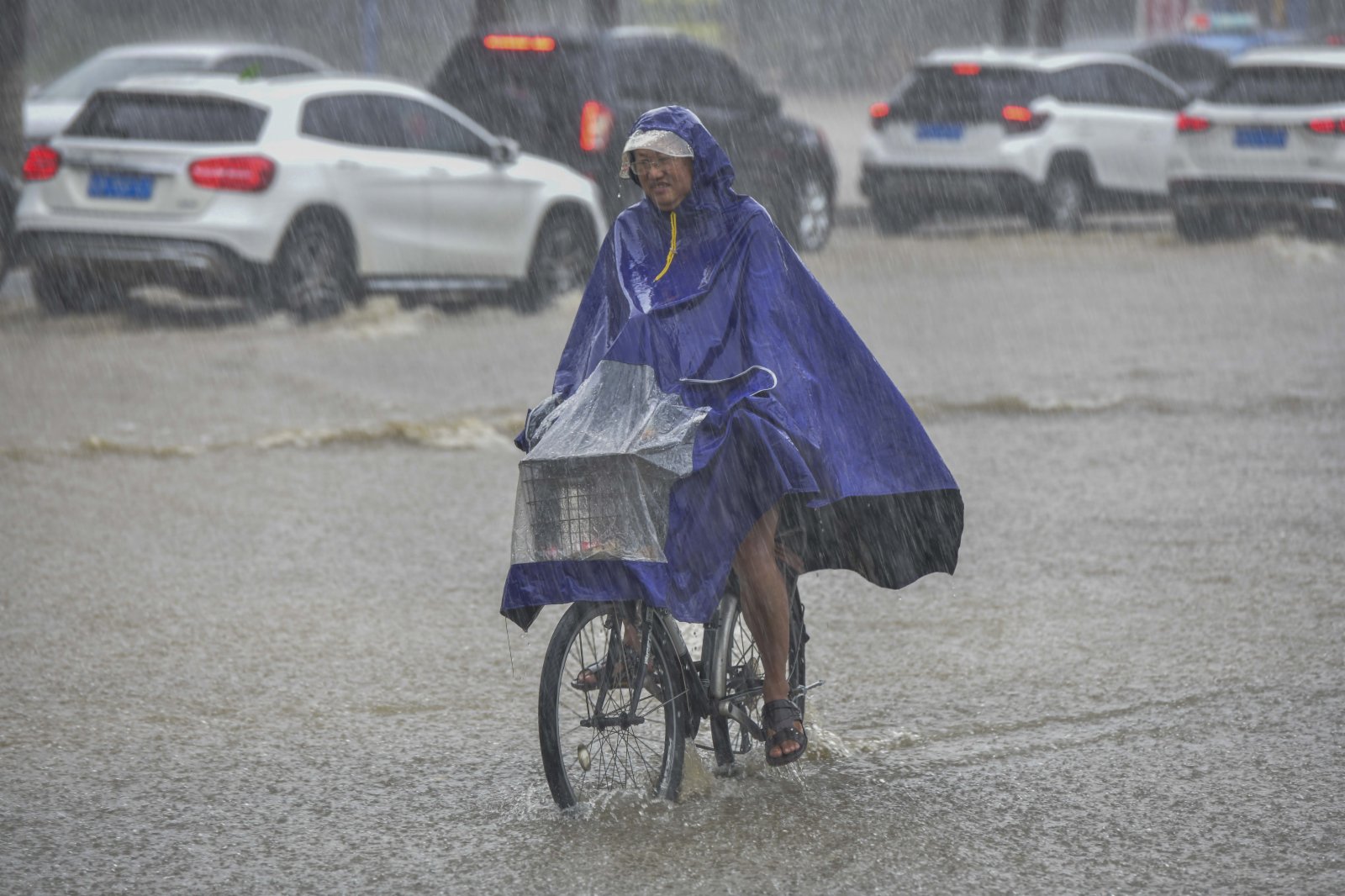 海口市突降暴雨，市民在雨中騎車出行。