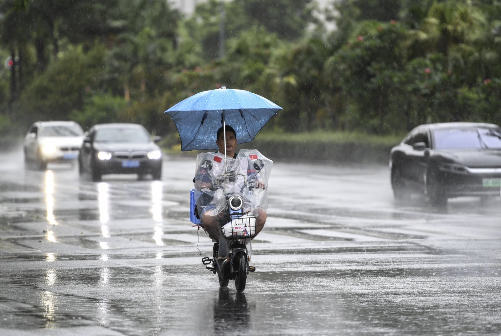 7月19日，居民騎着電動車在雨中前行。