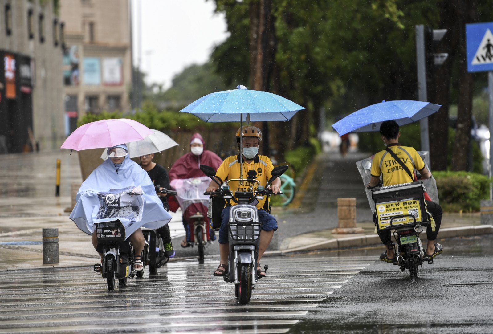 7月19日，居民騎着電動車在雨中前行。