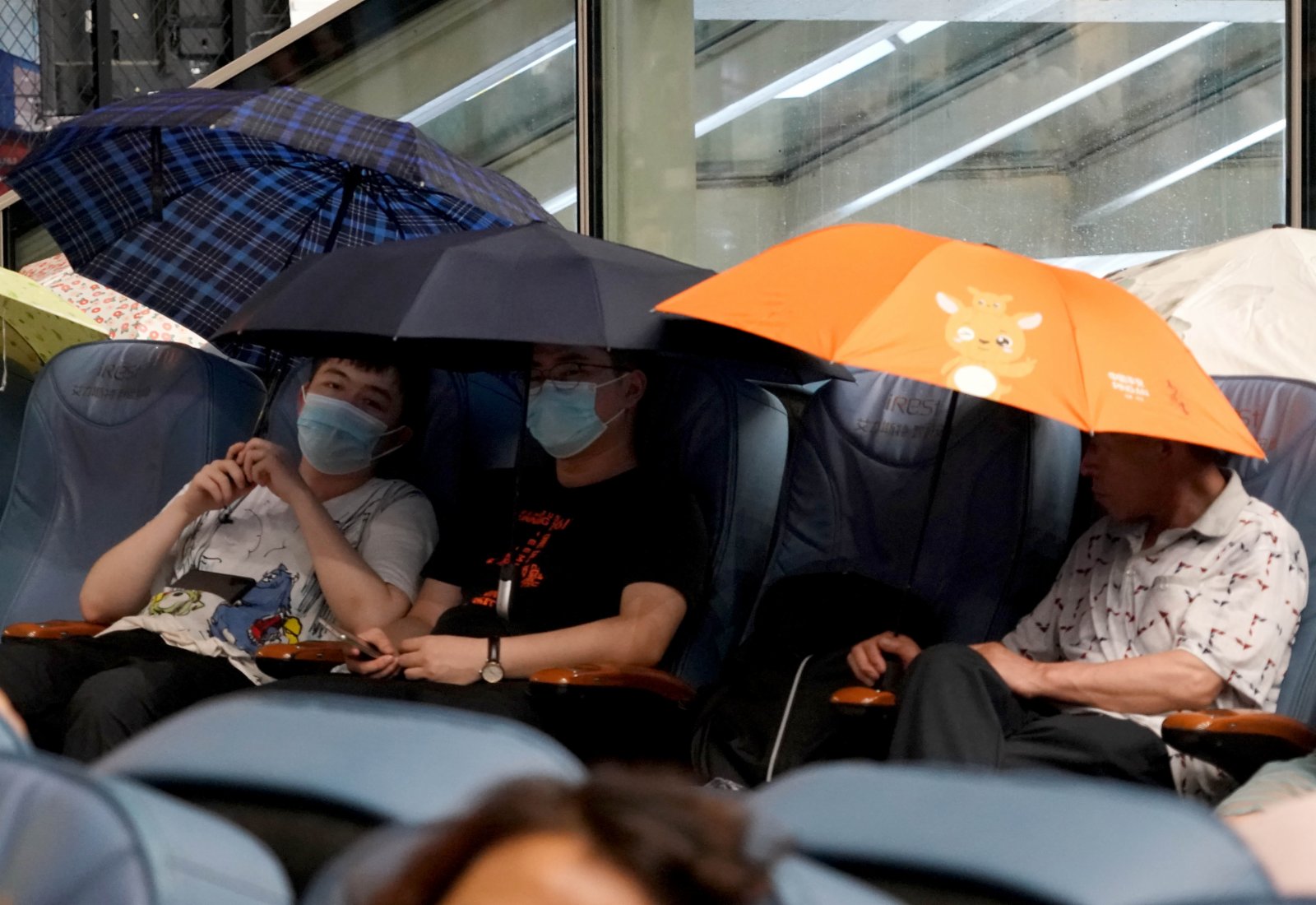 7月20日，旅客滯留在鄭州東站。候車廳出現漏雨情況，旅客撐傘擋雨。（新華社）