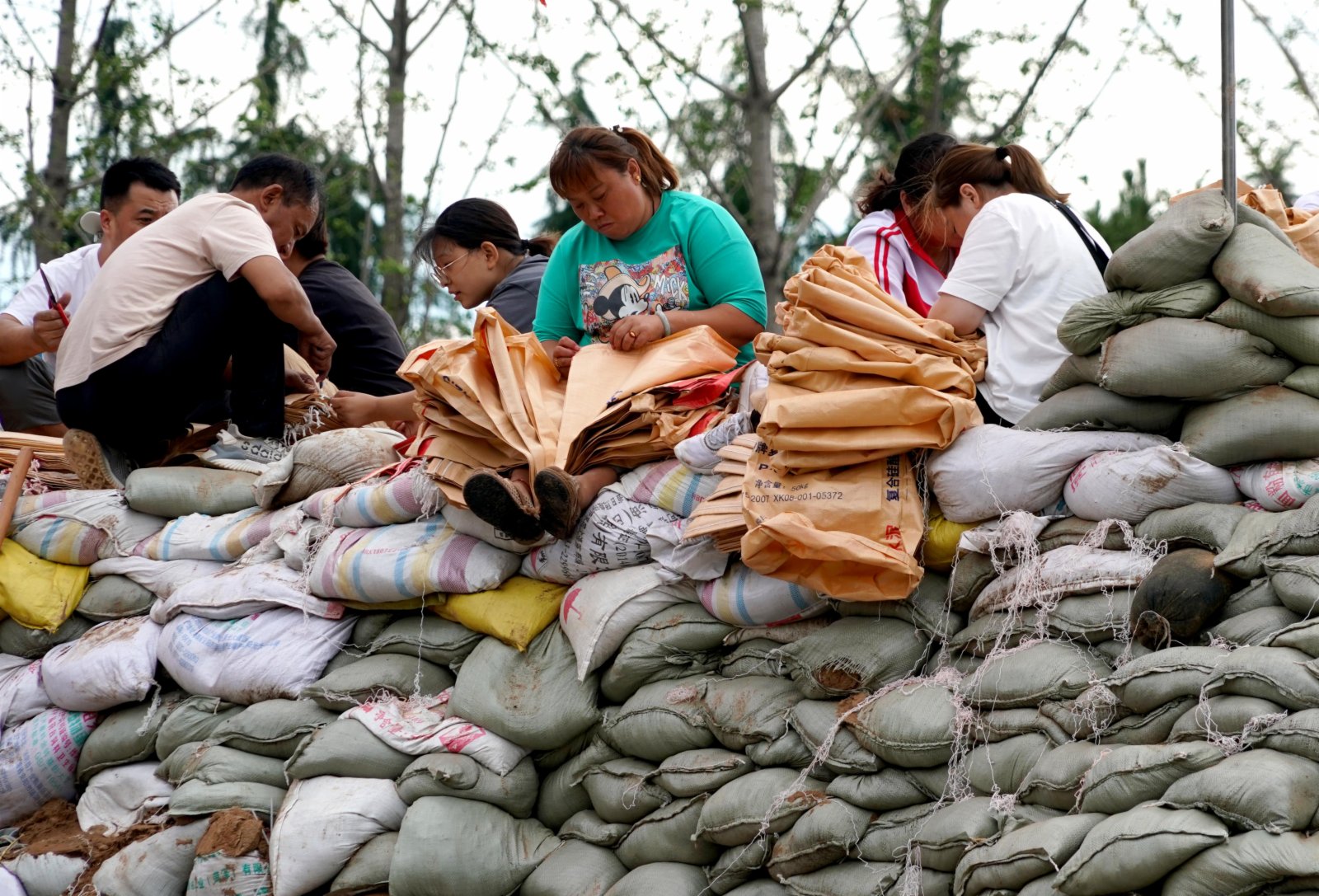 7月29日，群眾在浚縣傅莊堤上為救援人員準備沙袋裝沙。（新華社）