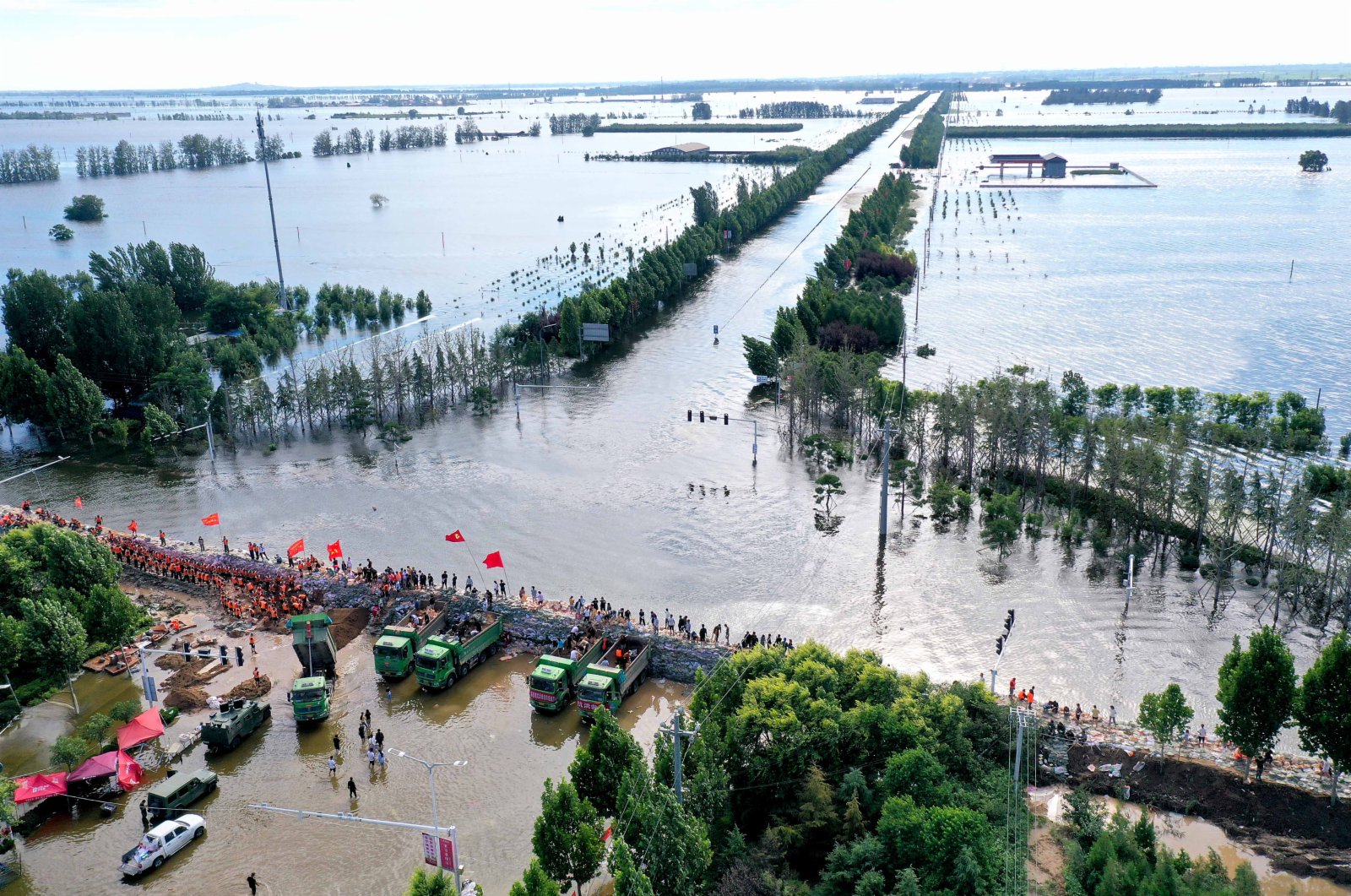 7月29日，在浚縣傅莊堤上，救援人員和群眾一起填裝沙袋，加固大堤（無人機照片）。（新華社）