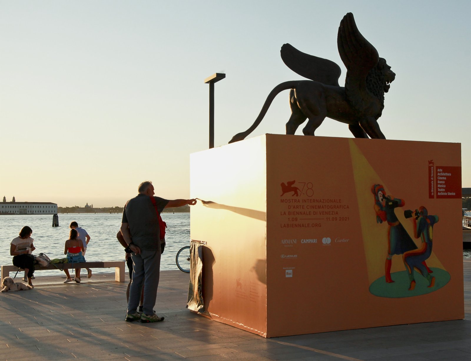 9月1日，在意大利威尼斯利多島，人們閱讀第78屆威尼斯國際電影節的海報。（新華社）