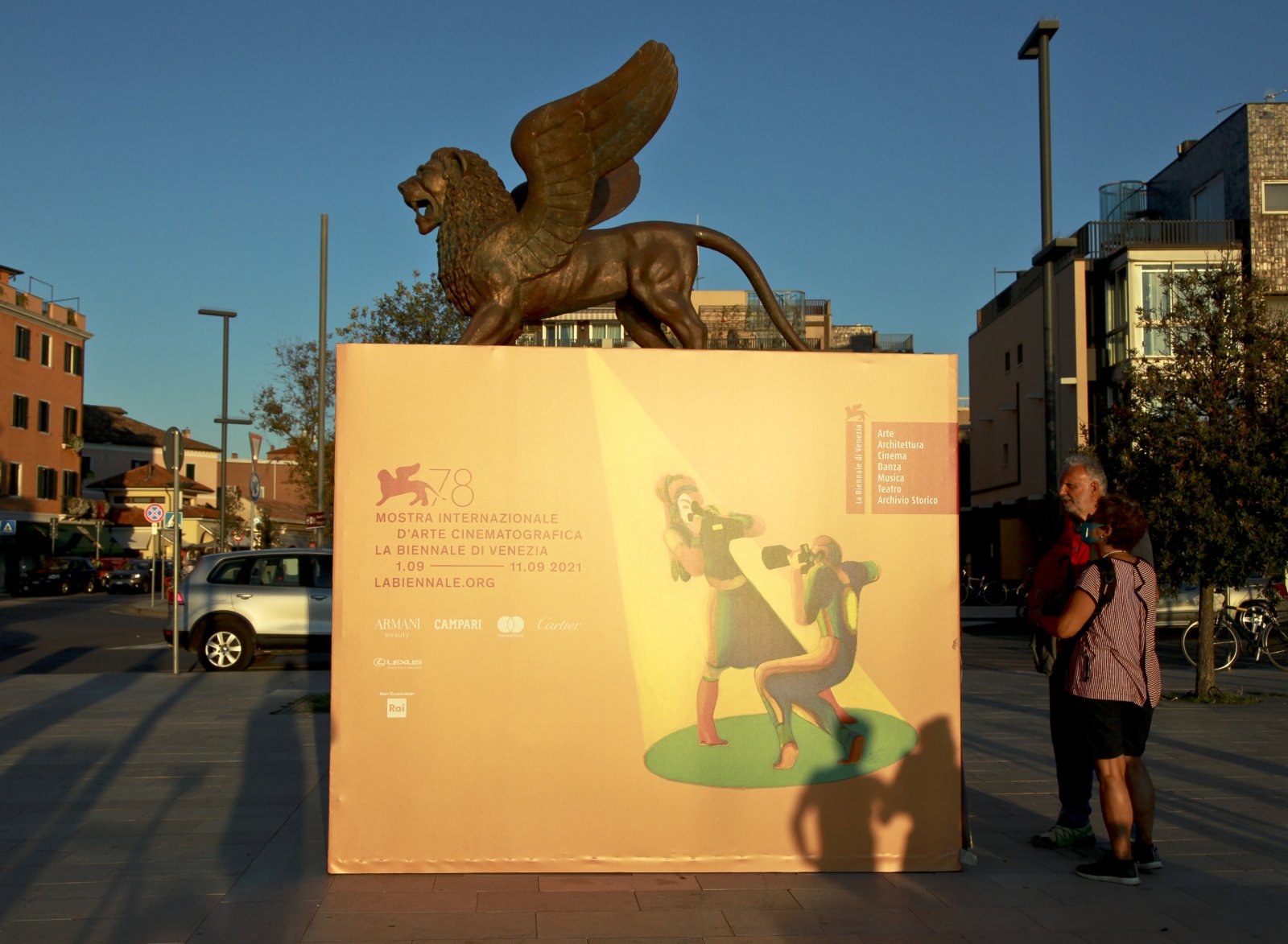 9月1日，在意大利威尼斯利多島，人們閱讀第78屆威尼斯國際電影節的海報。（新華社）