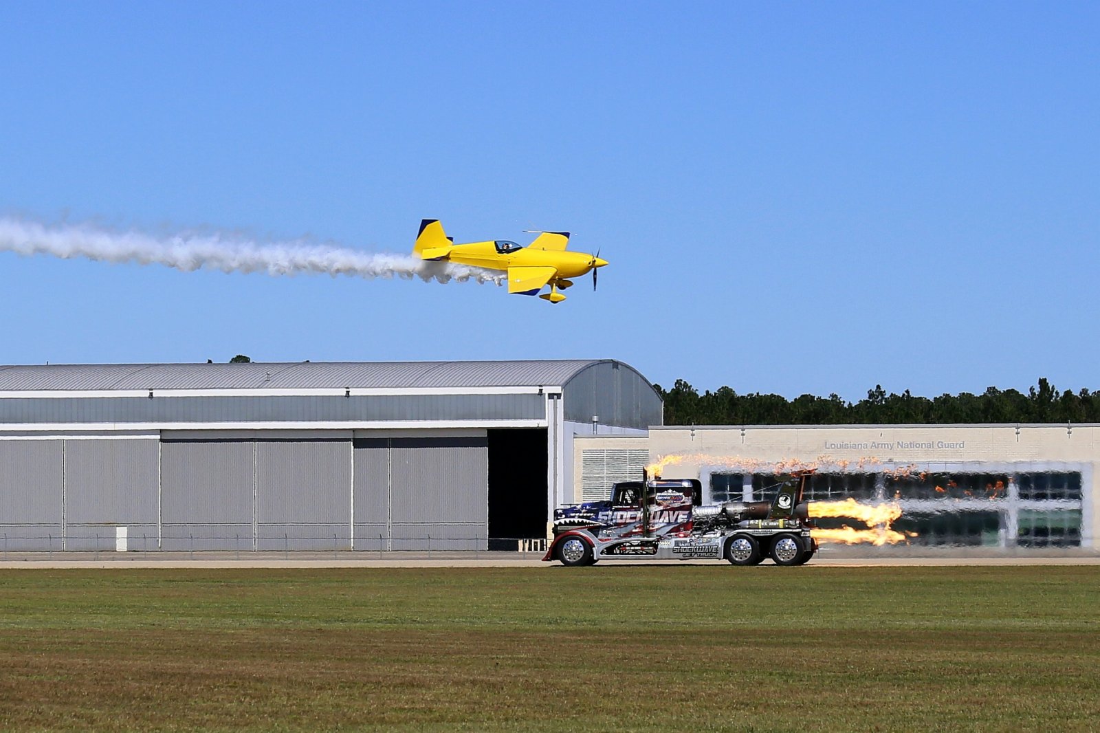 10月16日，在美國路易斯安那州哈蒙德北岸地區飛行秀現場，特技飛行員凱文·科爾曼駕駛Extra 300 SHP超高速飛機與衝擊波噴氣卡車同場競技。（新華社）