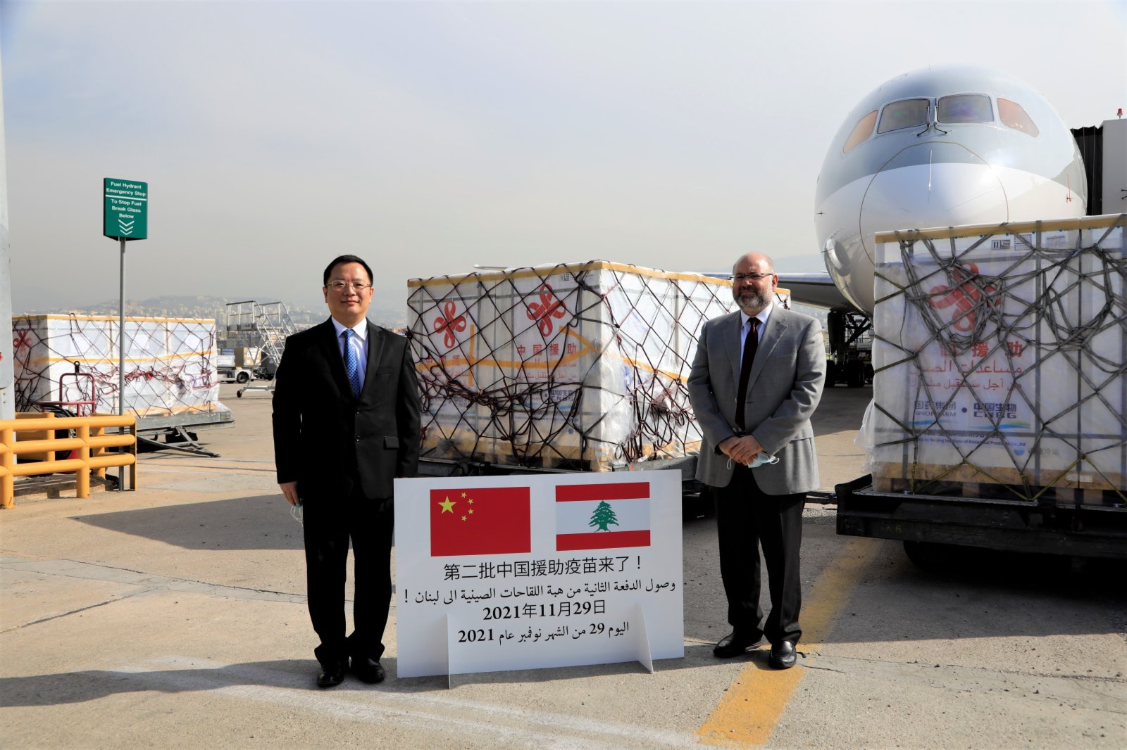 11月29日，在黎巴嫩貝魯特拉菲克·哈里里國際機場，中國駐黎大使錢敏堅（左）和黎公共衞生部長菲拉斯·阿卜亞德在中國援助疫苗前合影。（新華社）