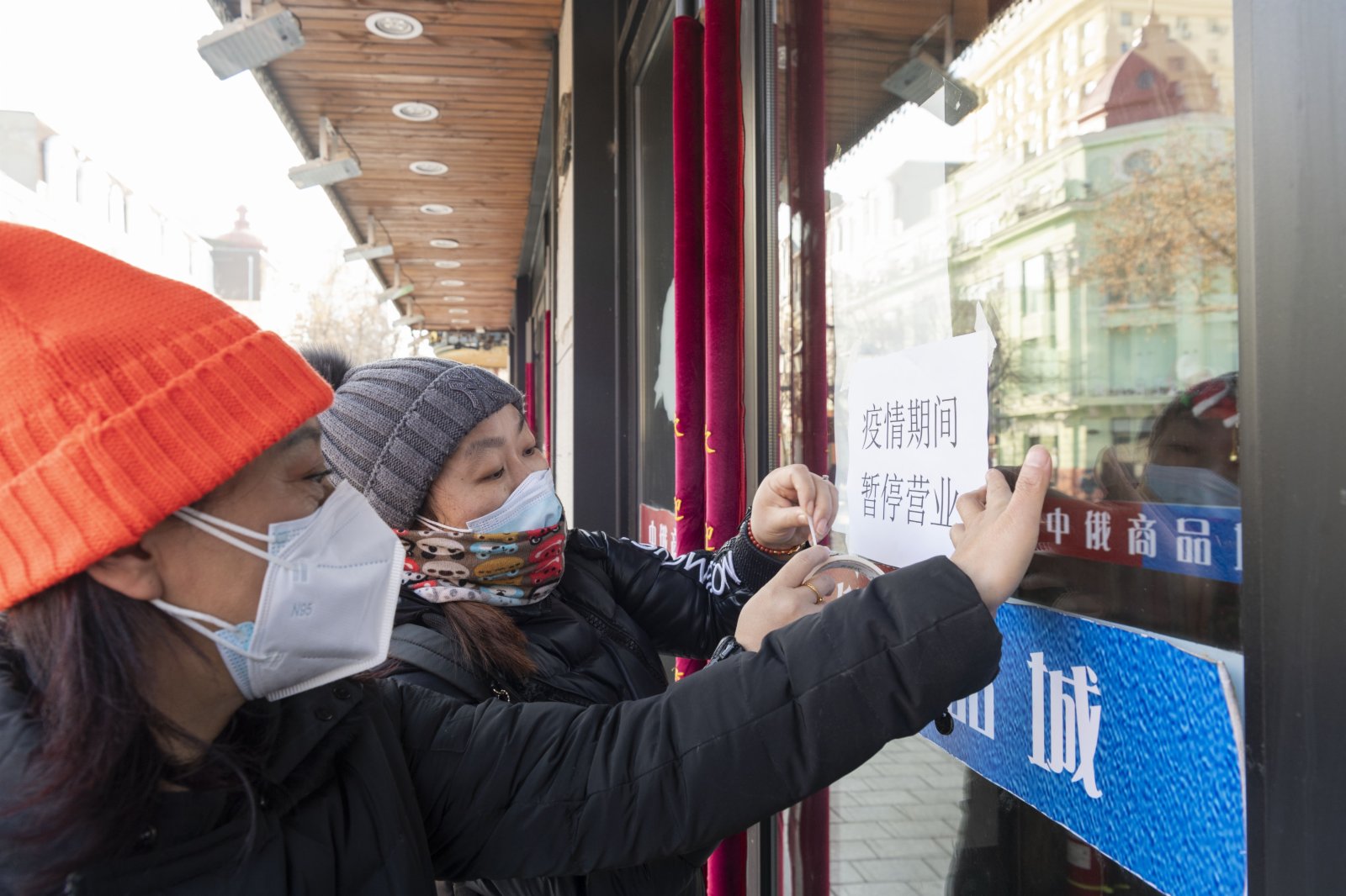 12月5日，在哈爾濱市中央大街，工作人員給商戶貼上「疫情期間 暫停營業」告示。